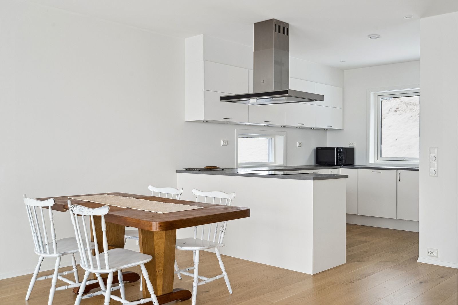 Lyst kjøkken med integrerte hvitevarer og spisestue.