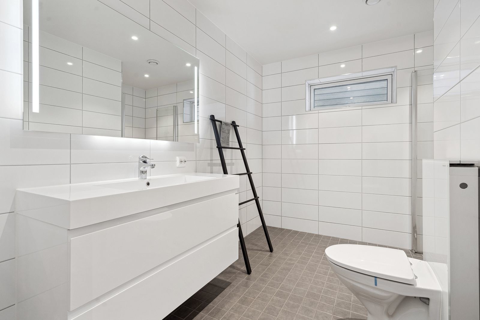 Bad 1 - Lekkert bad med flisbelagte vegger og gulv. Spotter i taket og speil med lys.