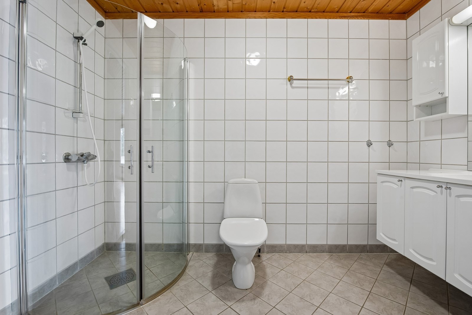Badet har dusjhjørne med skjermdører i herdet glass og opplegg for vaskemaskin. Galleribilde