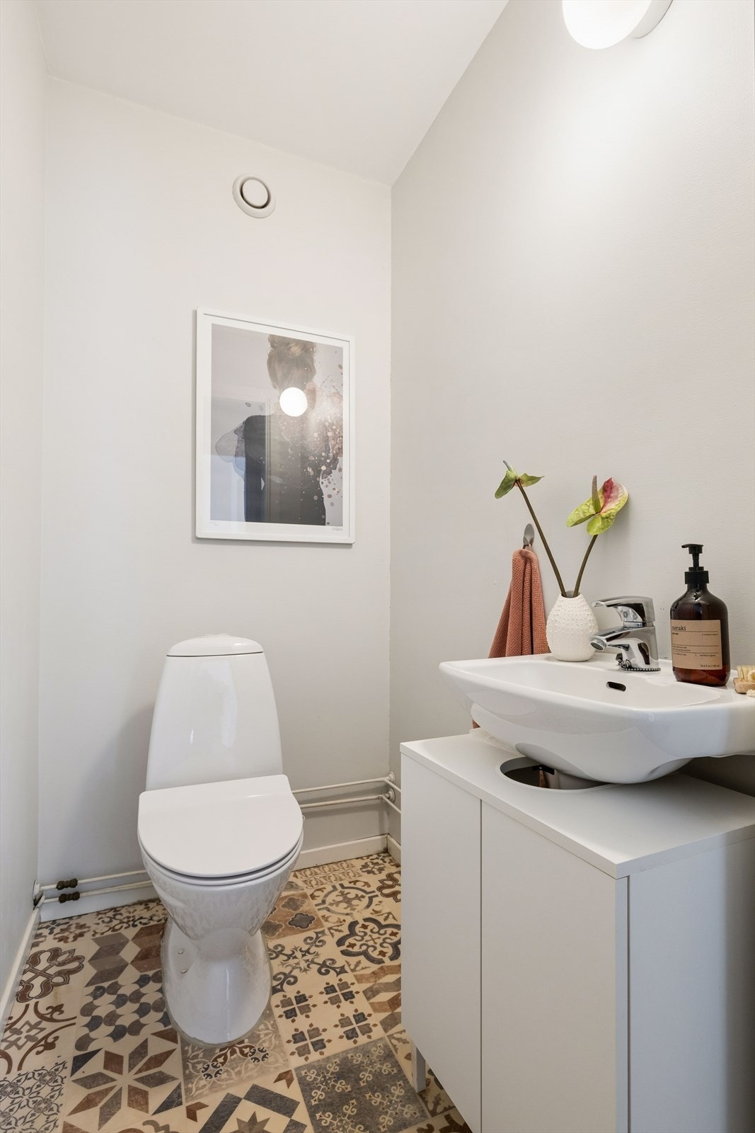 Separat toalettrom hvor innredningen består av servantskap med glatte, folierte fronter og servant. Lysarmatur på vegg og gulvmontert toalett. Galleribilde