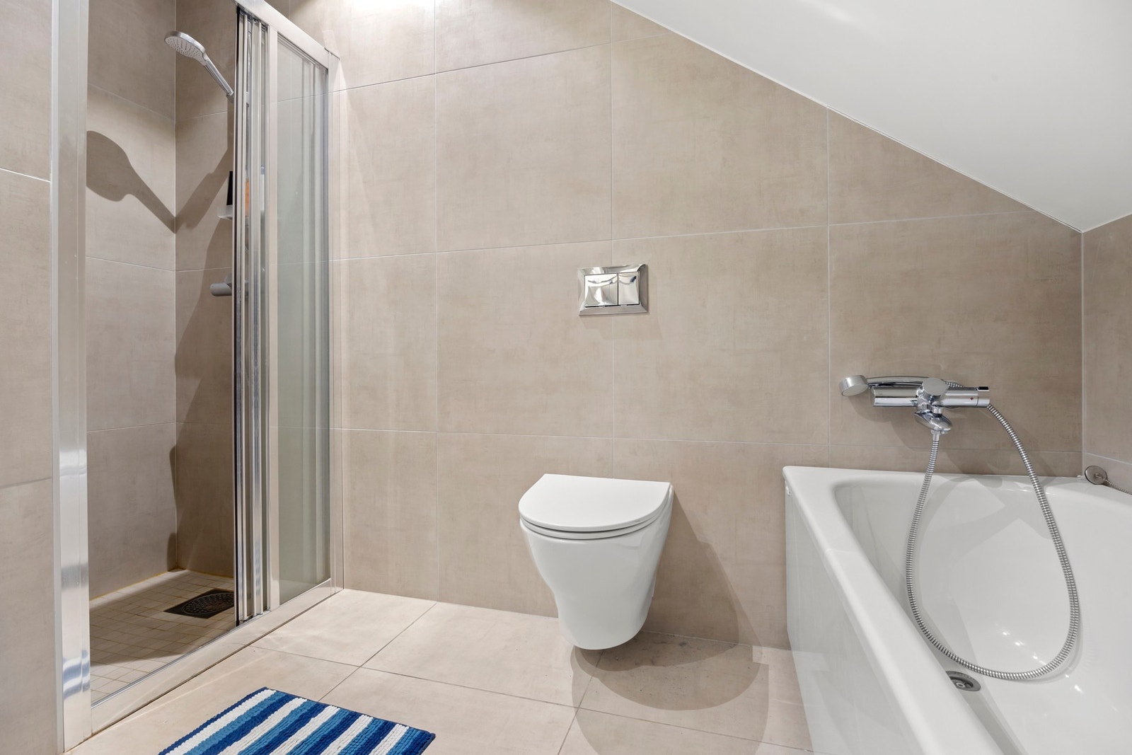 Badet i 2. etg har dusjhjørne og badekar, vegghengt toalett. Pent flislagt på gulv og vegg med 60x60 fli. Galleribilde