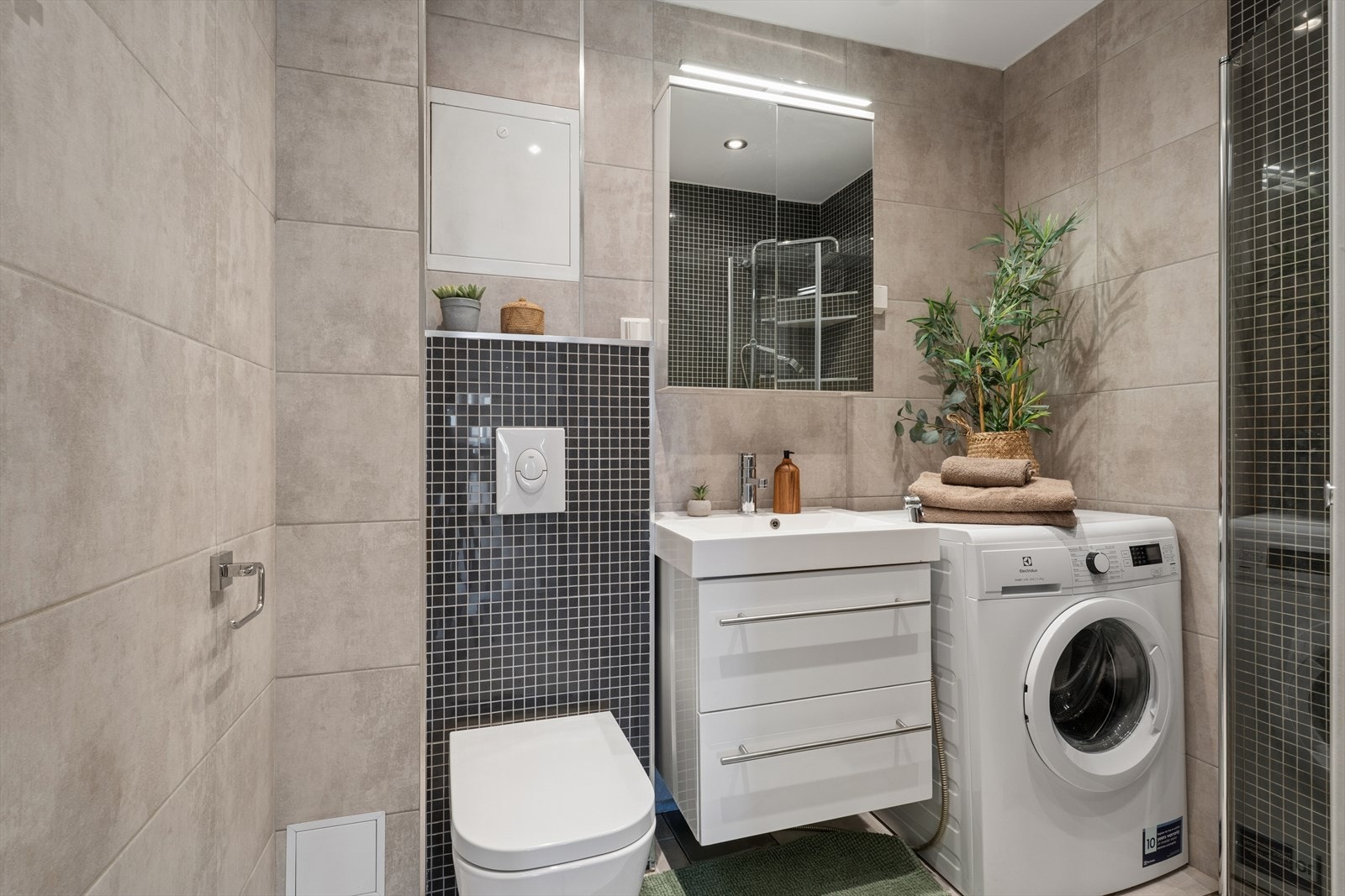 Badet er flislagt på vegger og gulv med elektriske varmekabler i gulvet og utført i lyse duse toner. Galleribilde
