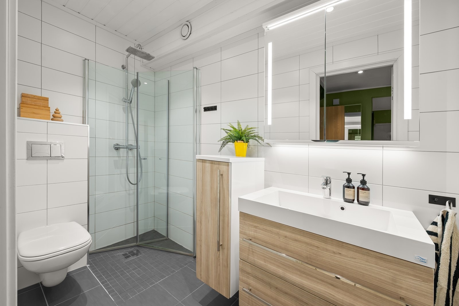 Badet i 1. etasje er pent og moderne innredet, med flislagte gulv og vegger i lyse, tidsriktige toner Galleribilde