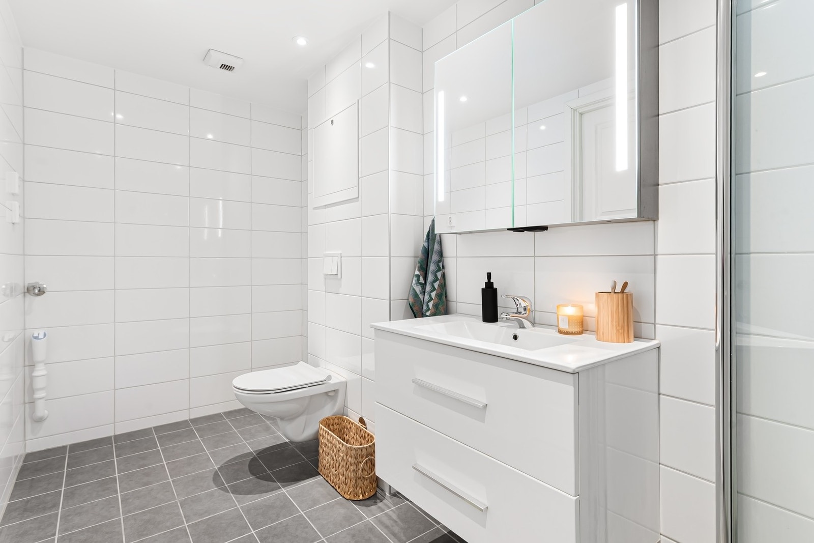 Badet er rehabilitert av borettslaget ca. 2019. Flislagt med varmekabler i gulv. Dusjnisje, hvit pen innredning med servant og speilskap, veggfestet WC og plass til vaskemaskin og tørketrommel Galleribilde