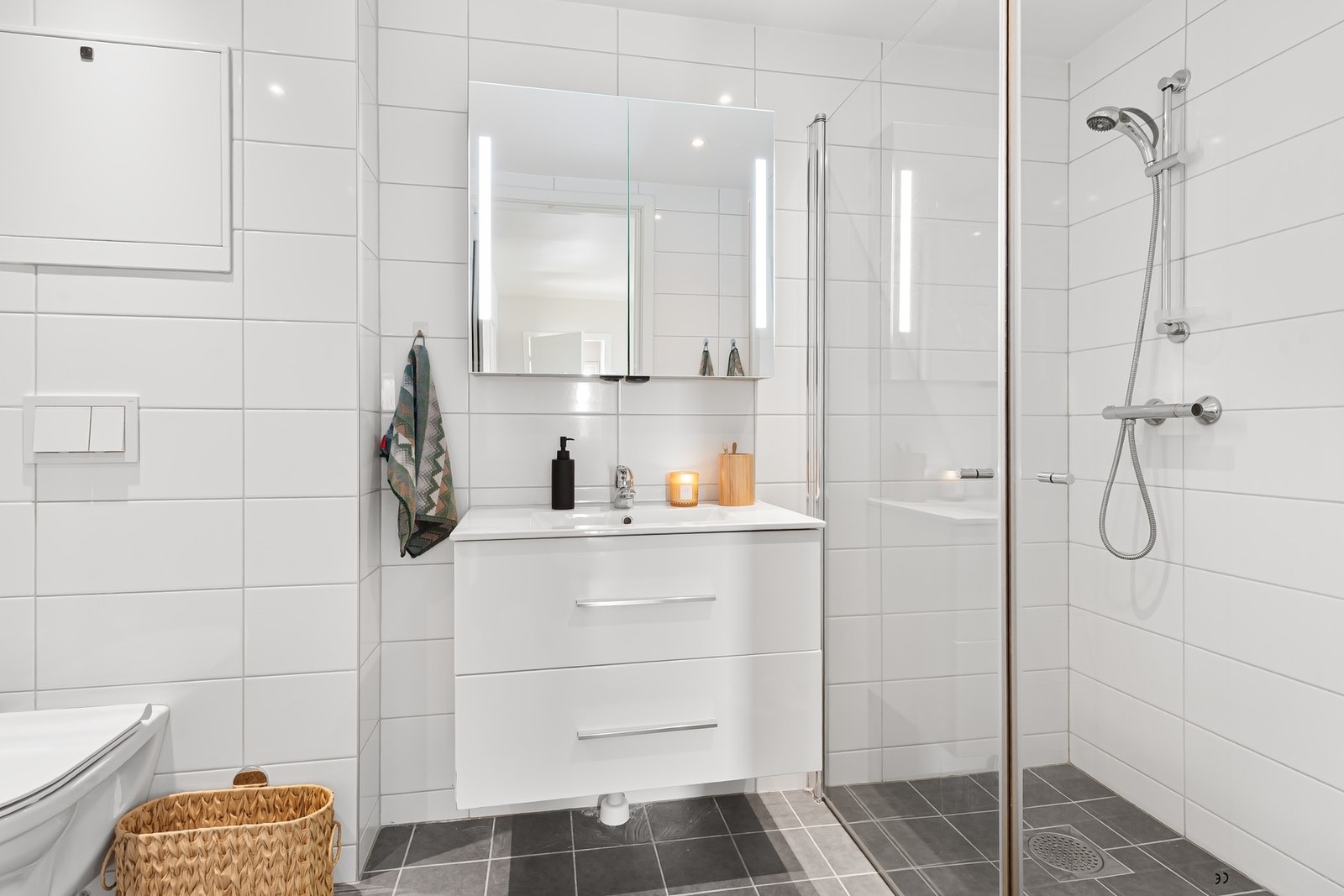 Badet er rehabilitert av borettslaget ca. 2019. Flislagt med varmekabler i gulv. Dusjnisje, hvit pen innredning med servant og speilskap, veggfestet WC og plass til vaskemaskin og tørketrommel Galleribilde
