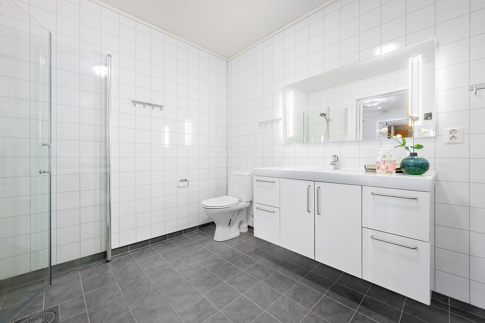 Badet er utstyrt med flott baderomsinnredning med nedfelt servant, toalett og dusjhjørne med innfellbare dører. Galleribilde