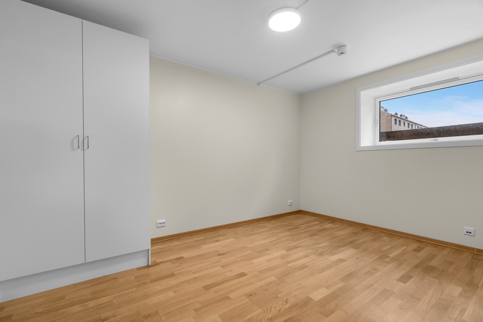 Soverom med lysmalte flater og plass til seng og oppbevaring Galleribilde