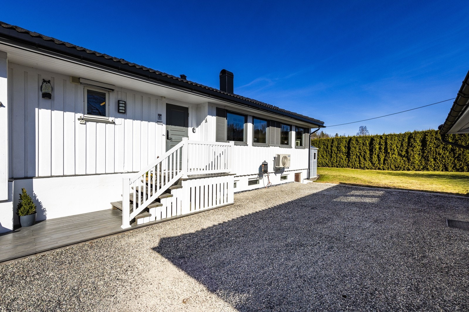 Gruset gårdsplass med adkomst til boligens inngangsparti og gode parkeringsmuligheter. Galleribilde