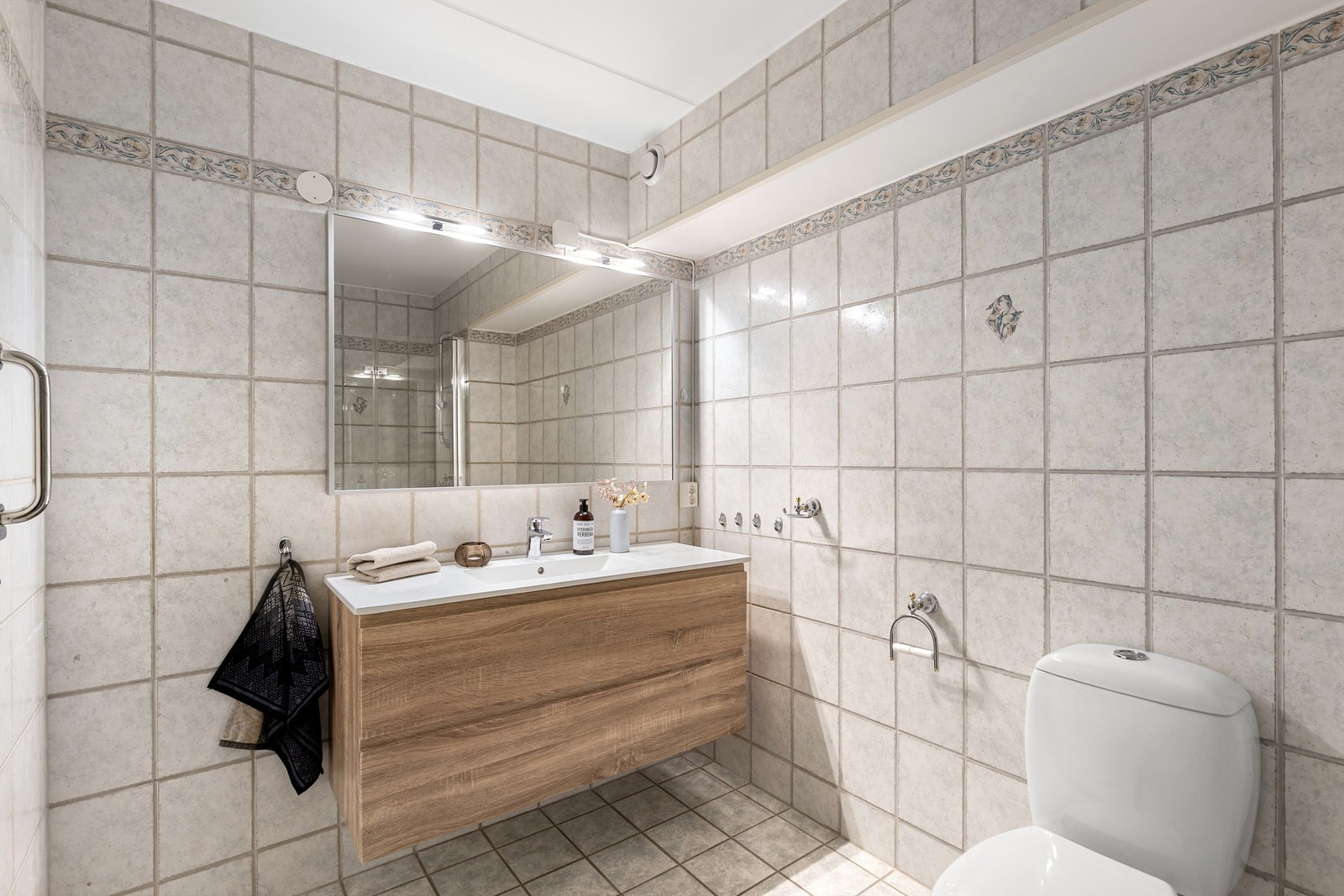 Vegger og gulv er flislagt med gulvvarme, badet er videre utstyrt med gulvstående WC, dusj og stort servantmøbel med speil med belysning. Galleribilde