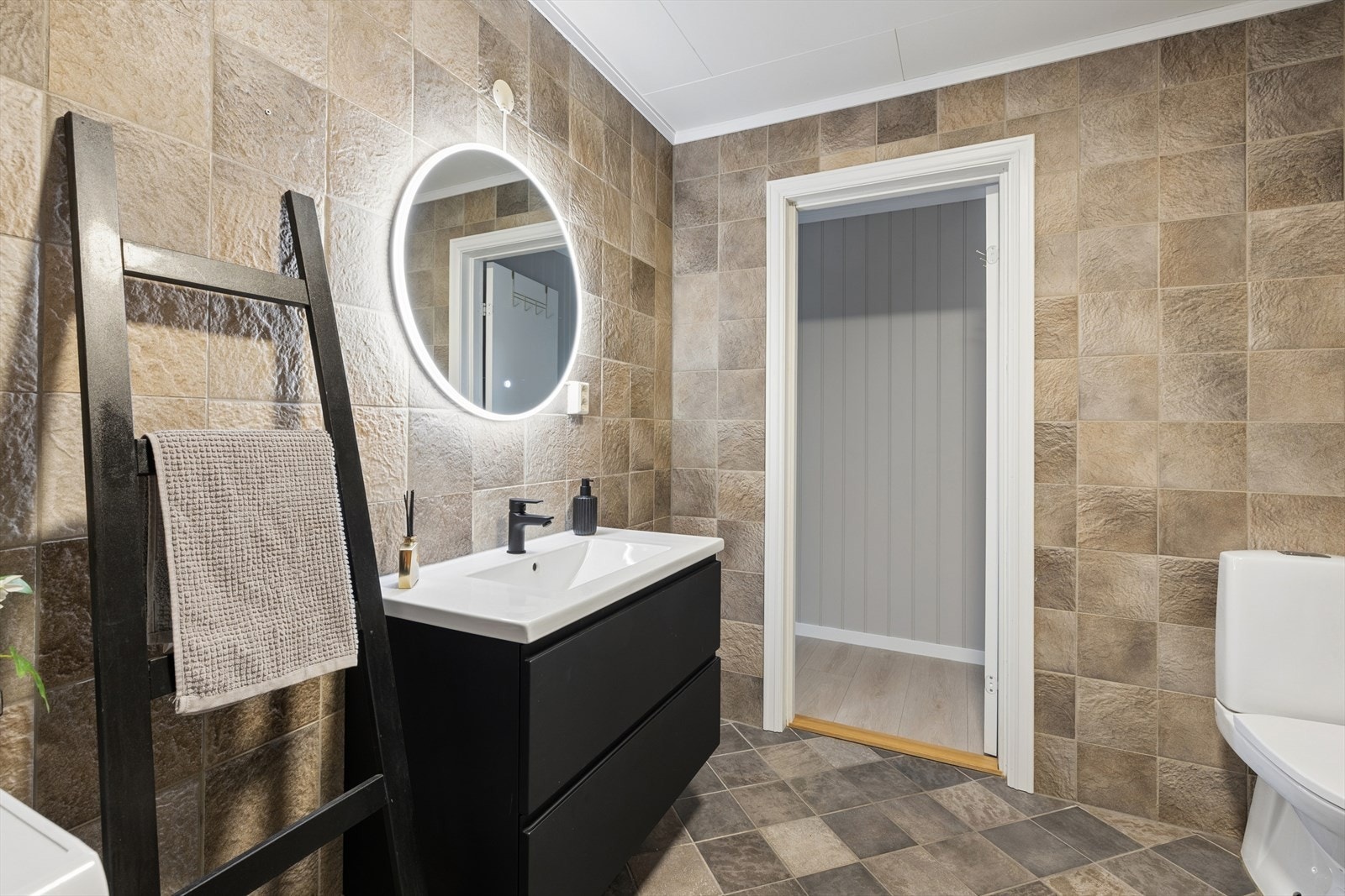 Lekkert og moderne baderom med flislagte overflater. Rommet gir et helhetlig og delikat uttrykk. Badet er utstyrt med varmekabler i gulvet Galleribilde