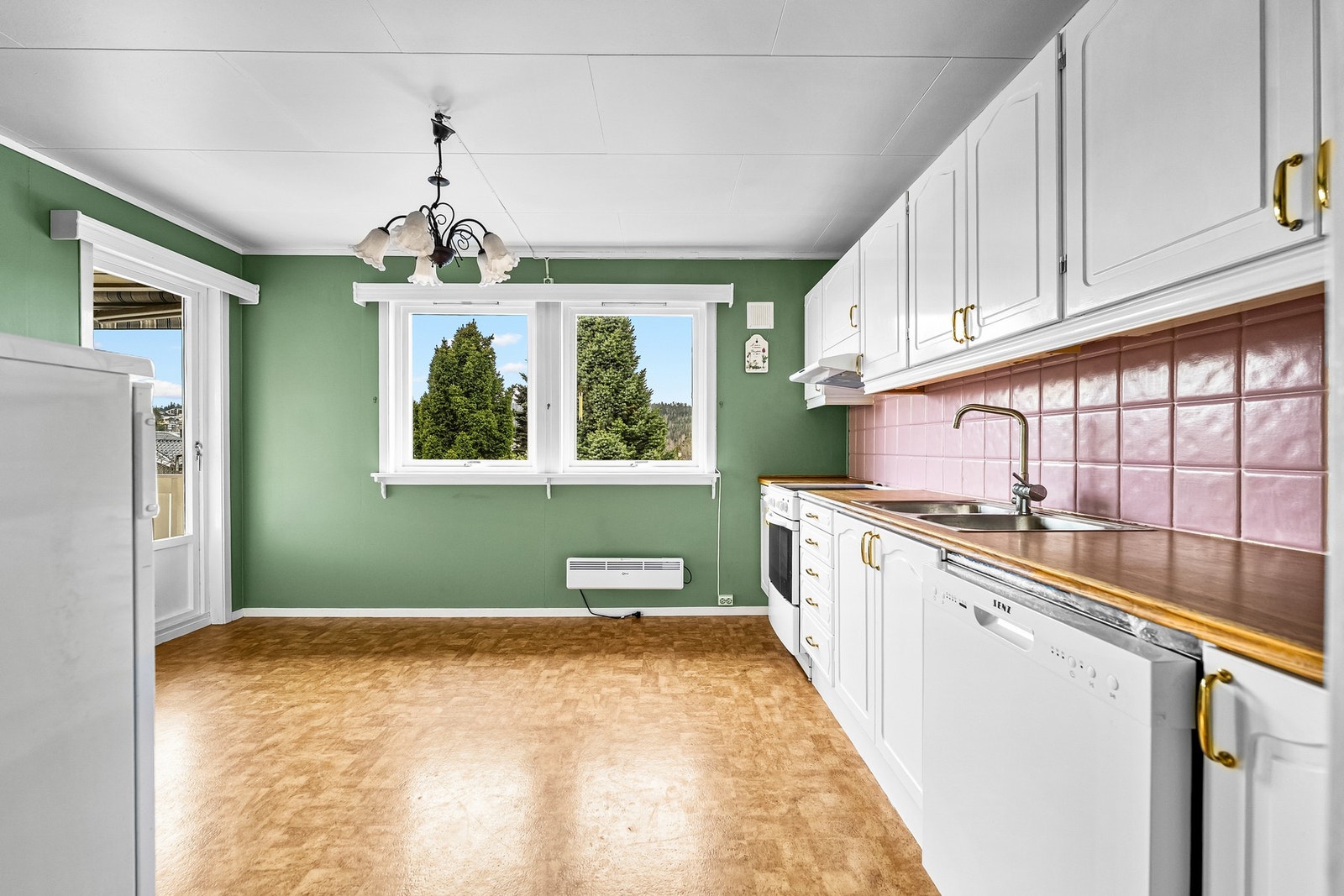 Innredningen har hvite, profilerte fronter og laminert benkeplate med nedfelt oppvaskkum i rustfritt stål. Det er flislagt mellom over- og underskap. Galleribilde