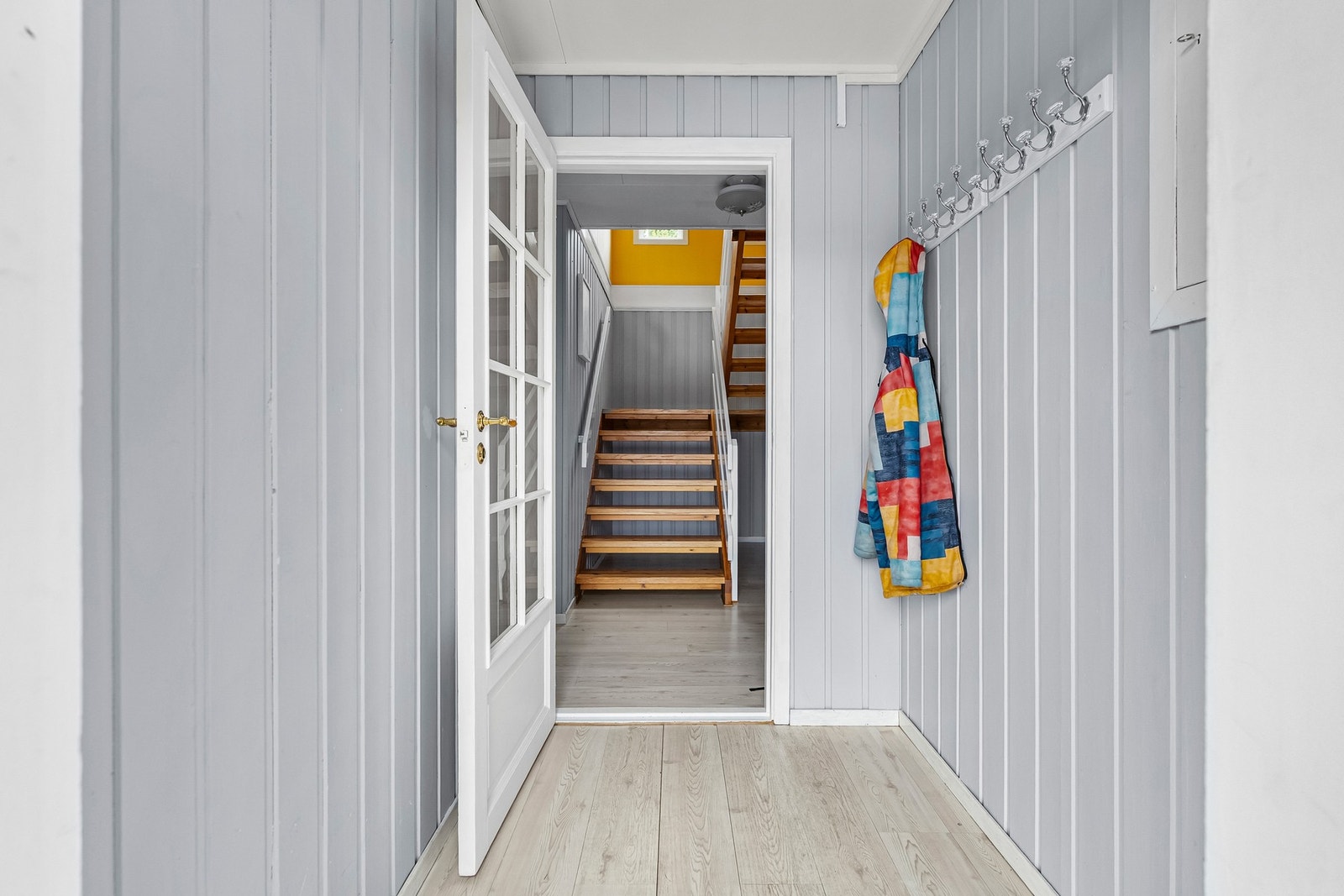 En hyggelig entré med malte panelvegger og laminatgulv ønsker deg velkommen inn i boligen. Galleribilde