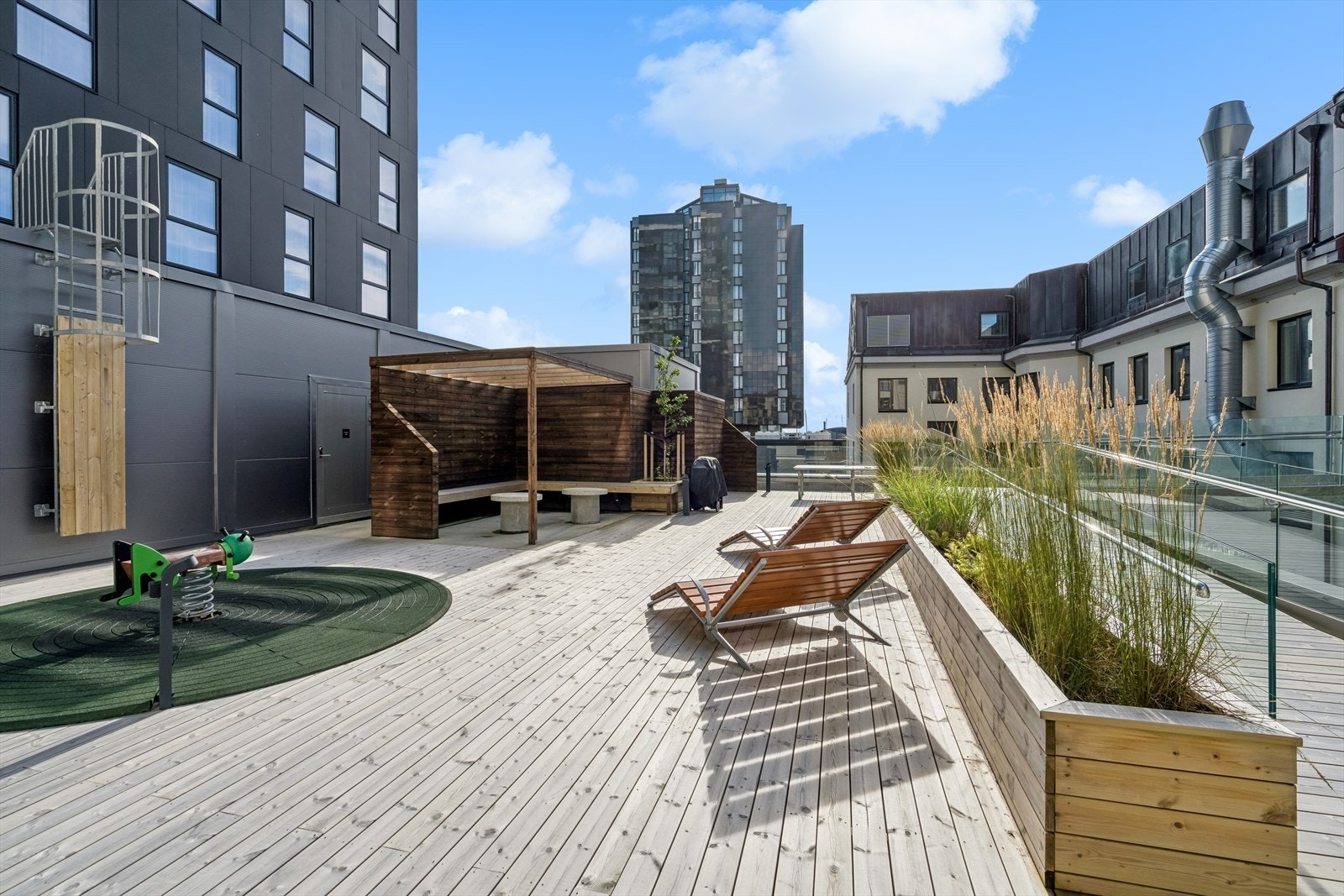Her er det loungestoler, pergola med sitteplasser og lekeapparat Galleribilde