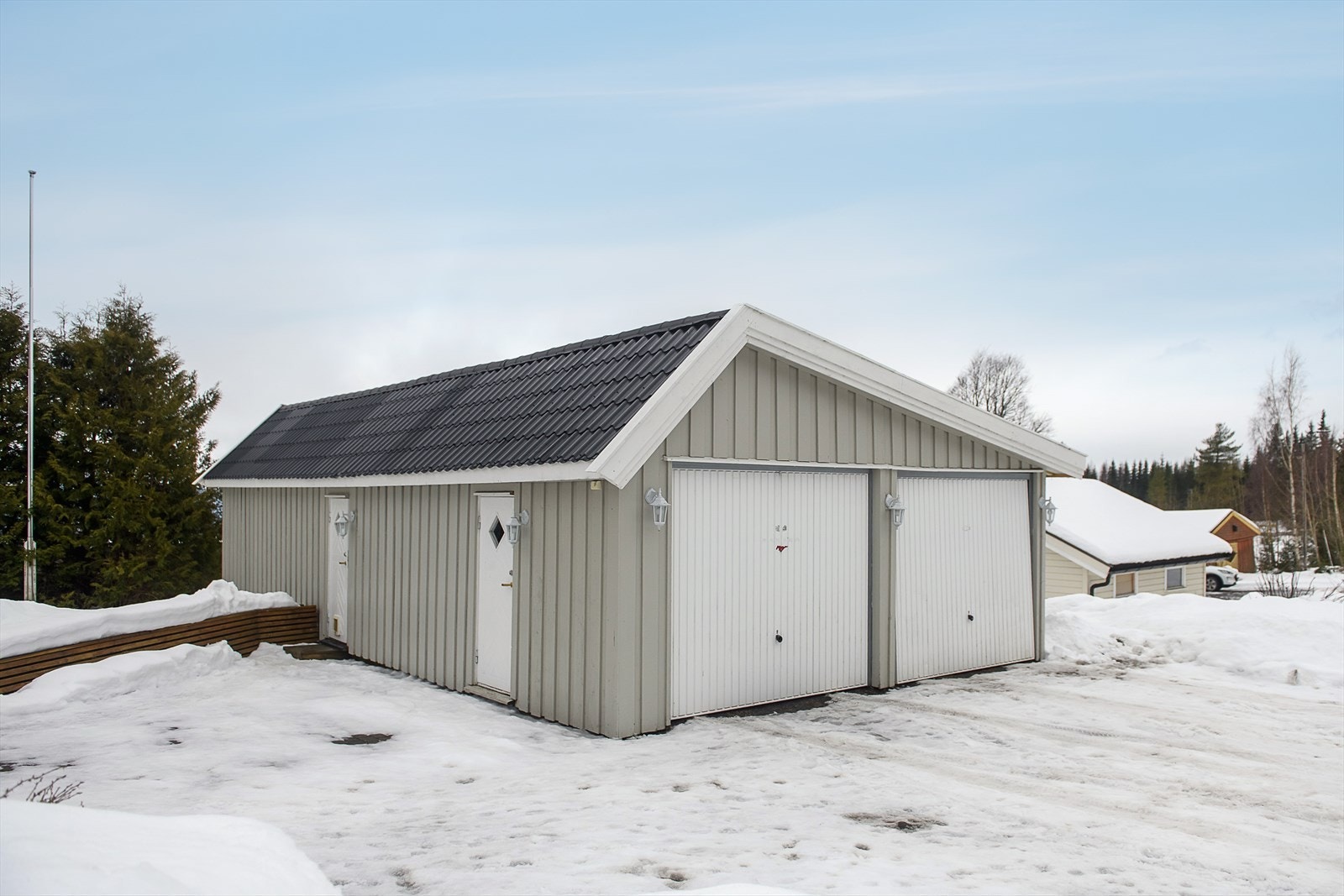 En stor, frittstående dobbelgarasje på 62 m² med to leddporter i stål og innredet hobbyrom. Galleribilde