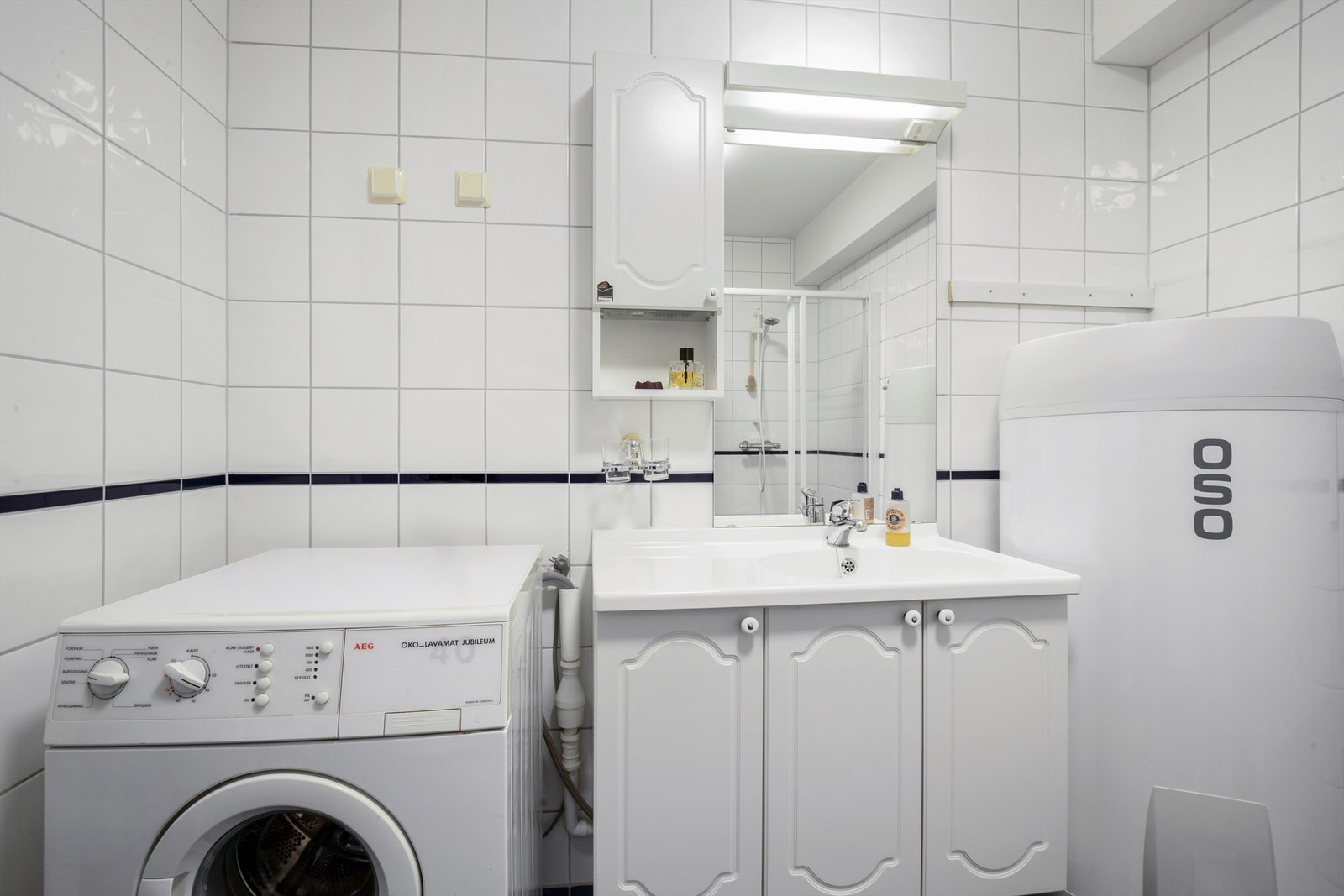Badet har vegghengt baderomsinnredning med profilerte lyse fronter og ny varmtvannsbereder Galleribilde