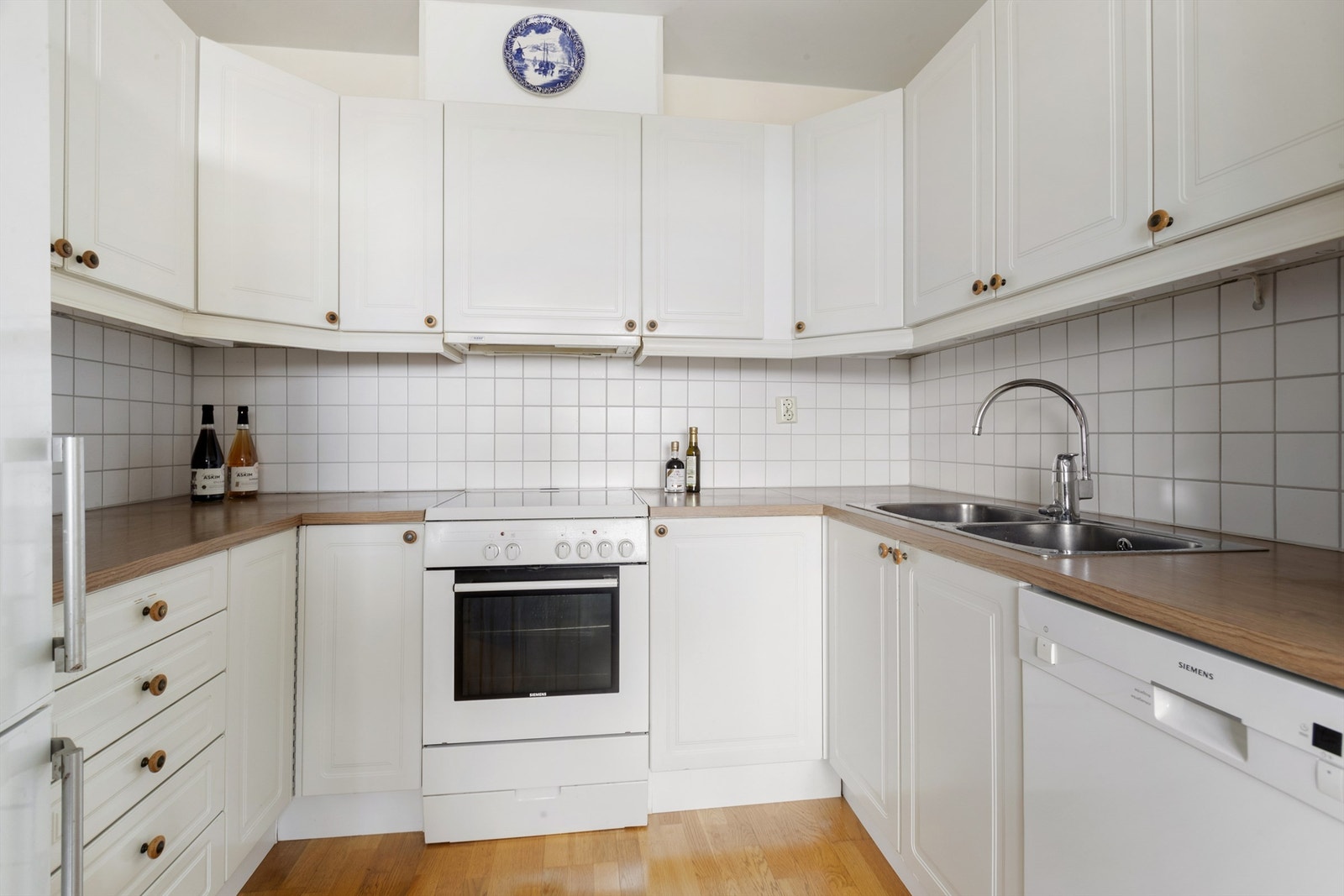 Lys kjøkkeninnredning fra byggeår med profilerte fronter og benkeplate av laminat. Hvitevarer medfølger Galleribilde