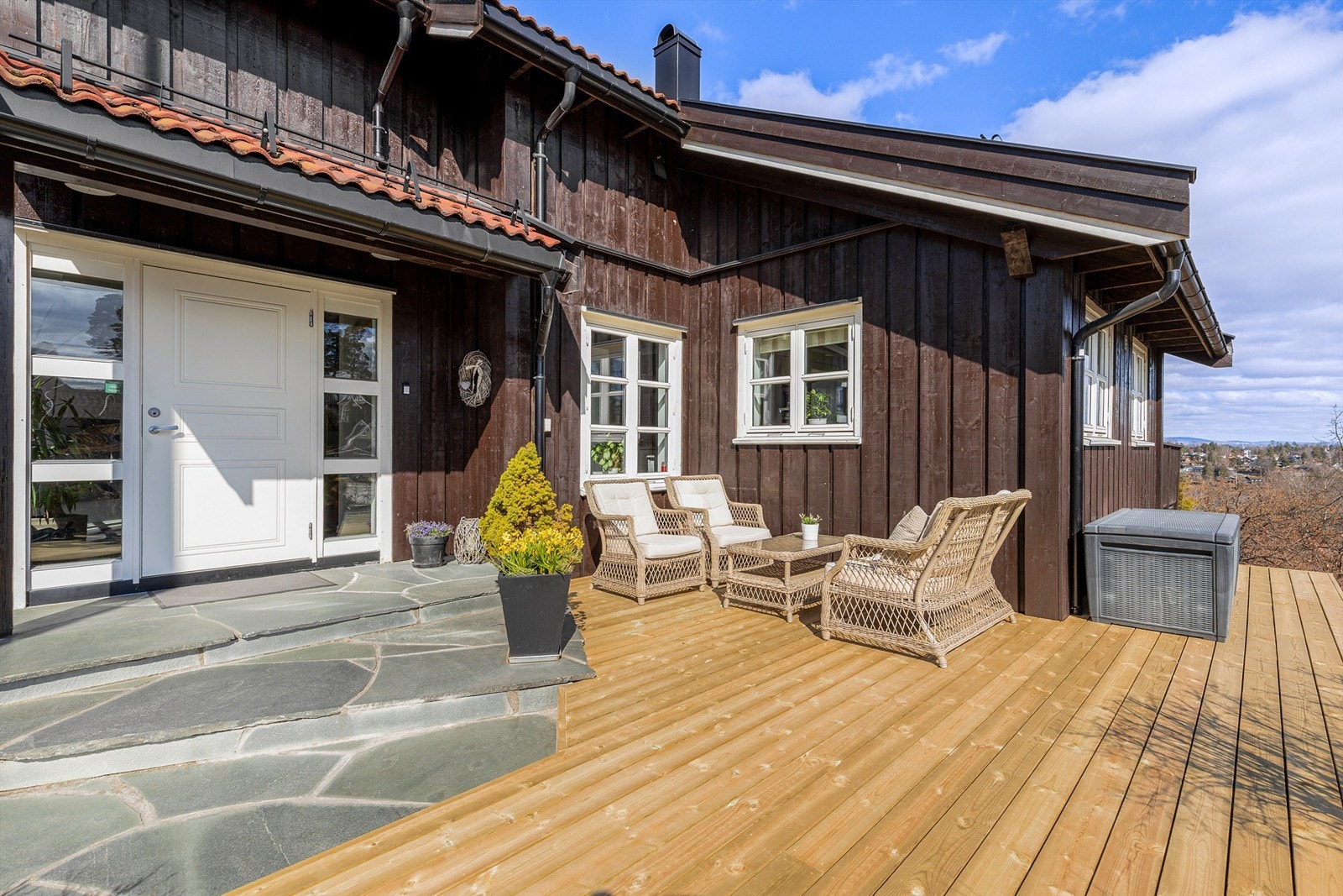 Inngangspartiet med terrasse og steinlagt trapp mot inngangsdøren. Galleribilde