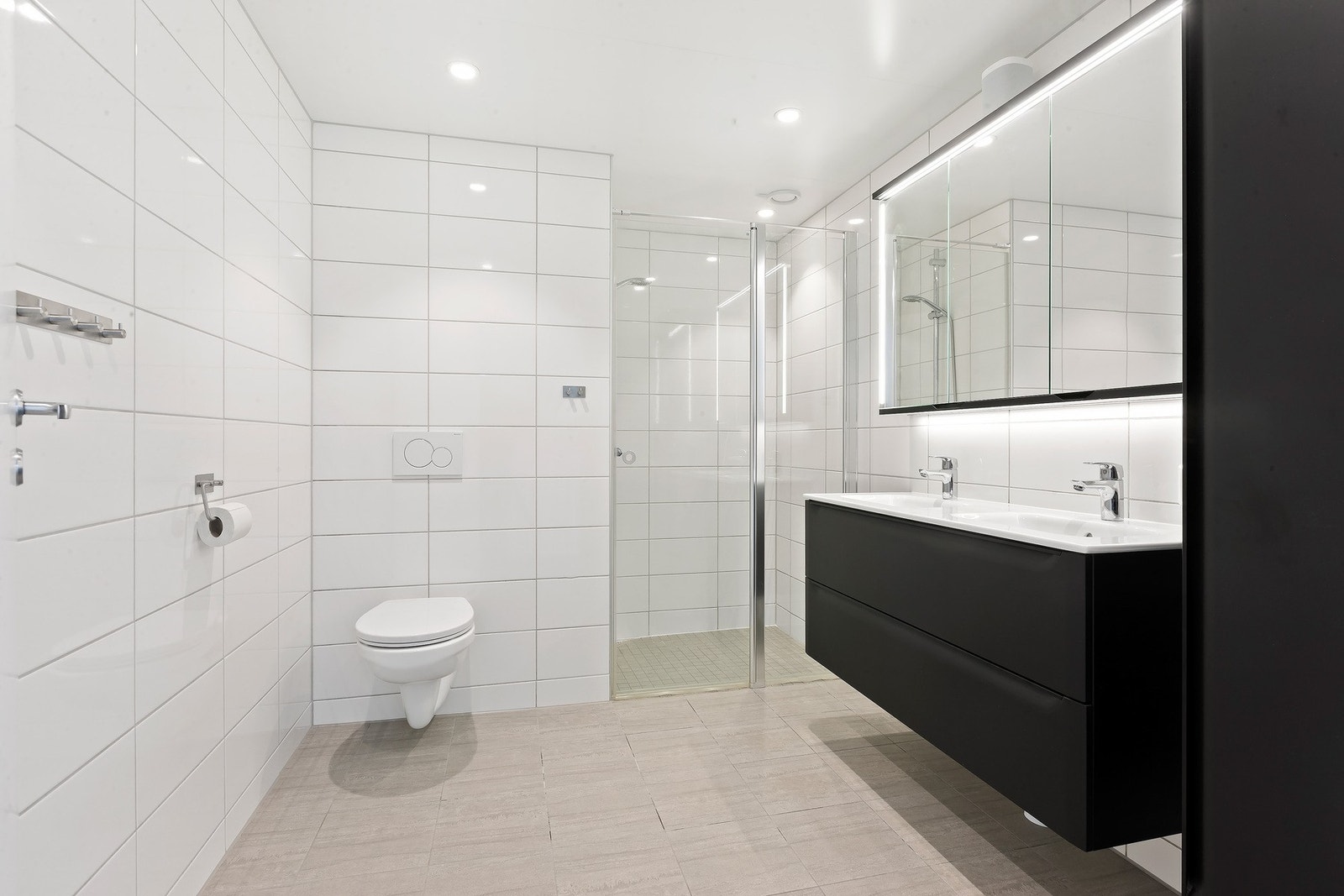 Badet er romslig og flislagt, med en praktisk og tidløs utforming Galleribilde