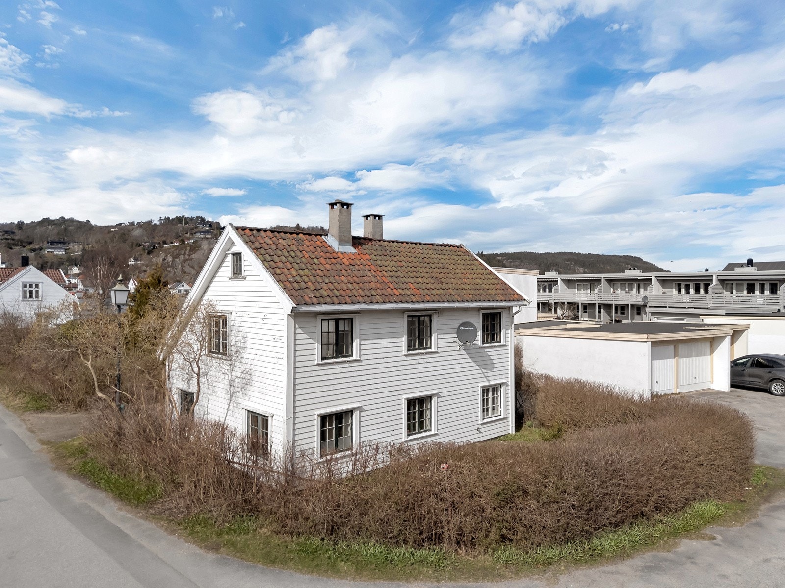 Tomten er opparbeidet med belegningsstein i innkjørsel, plen på fremsiden av boligen med hekk mot veien. Galleribilde