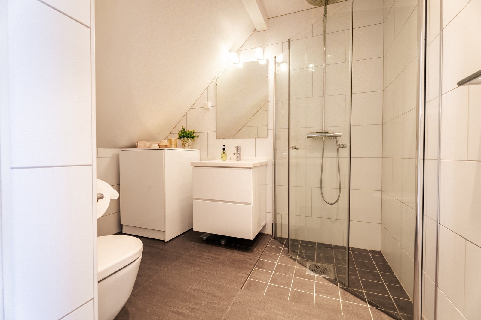 Totalrenovert bad i loftsetasjen med hvite fliser på vegg og mørkegrå fliser på gulv. Galleribilde