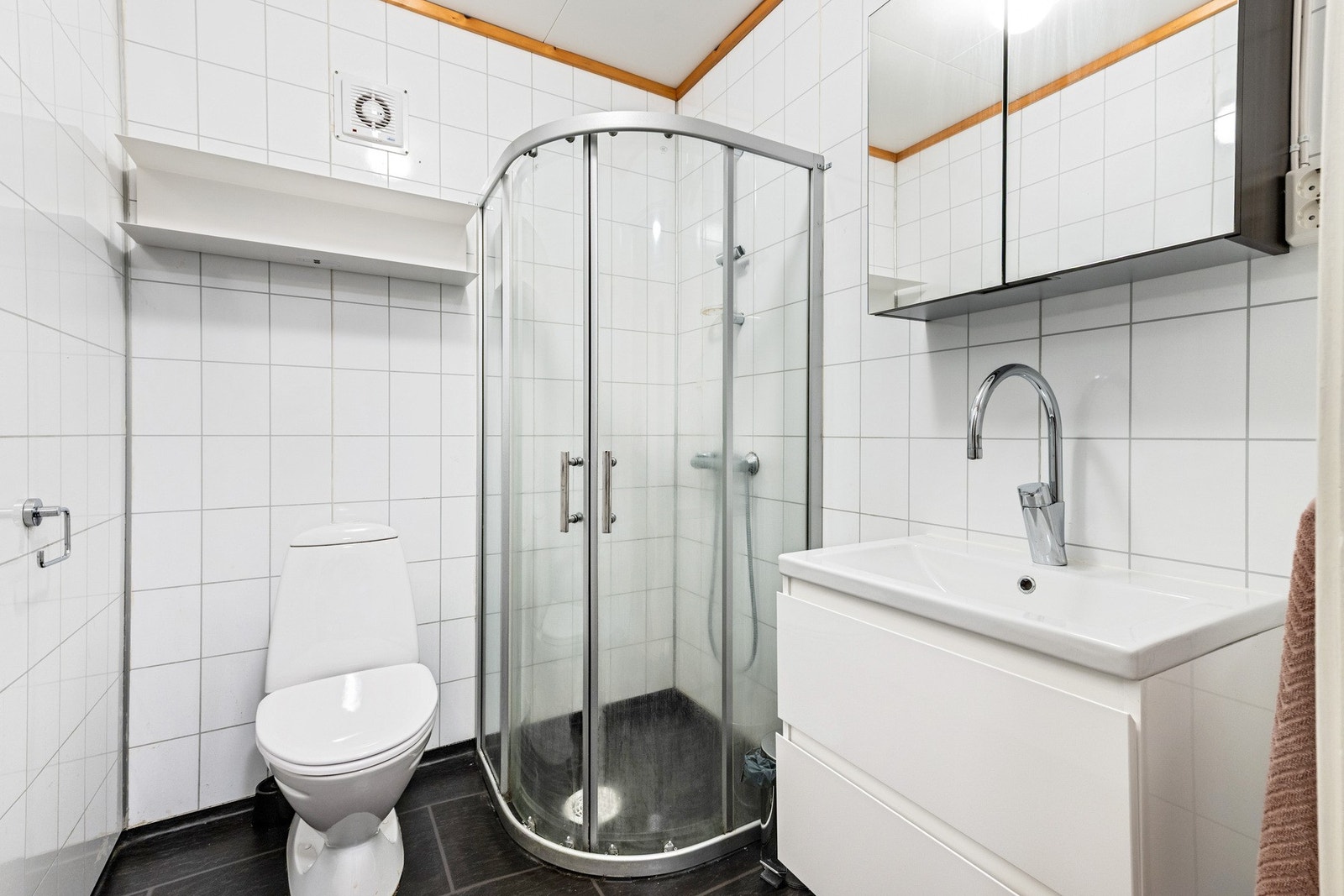 Bad med varmekabler i gulv. Badet er utstyrt med servantskap, veggdusj og gulvvmontert wc. Galleribilde