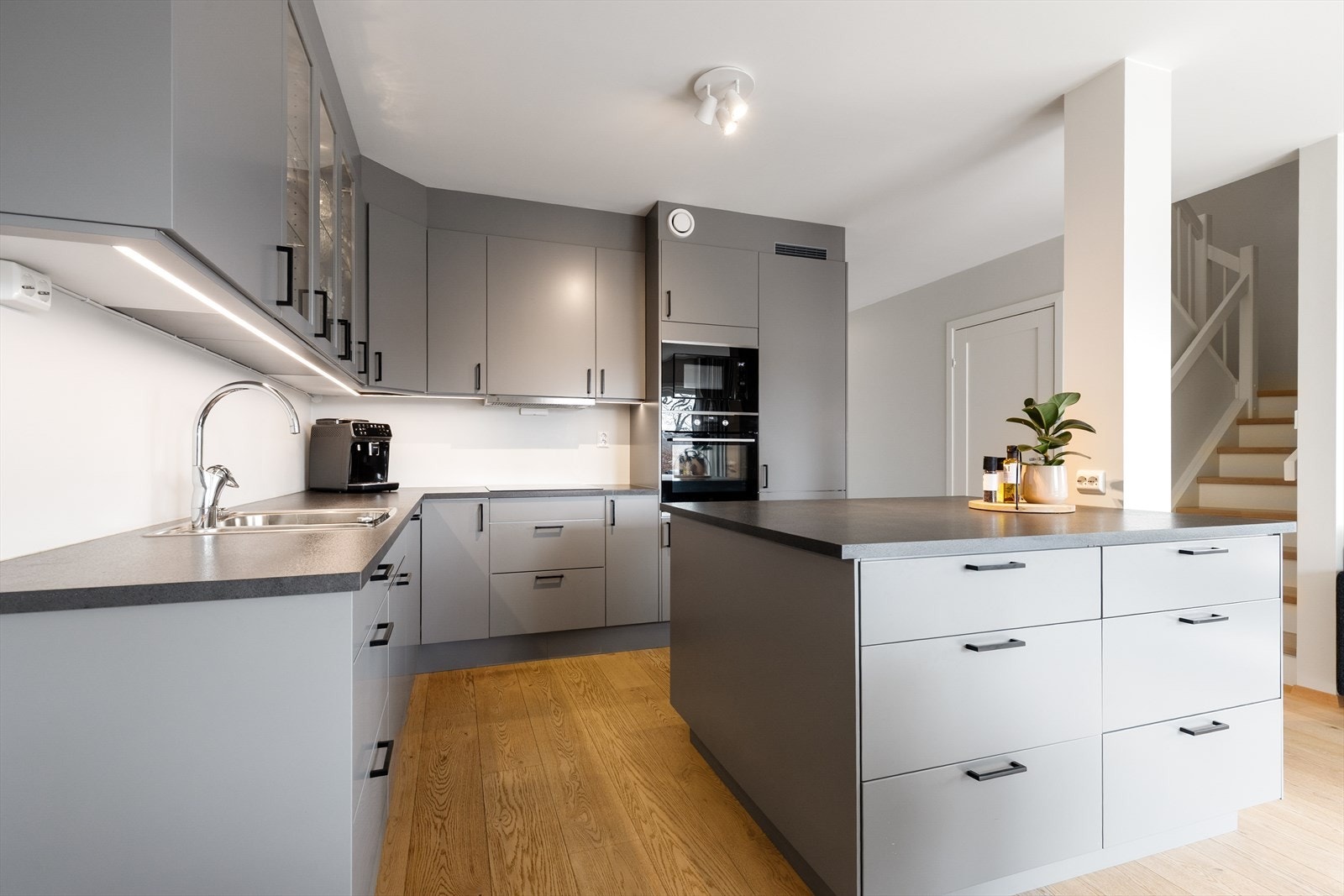 Kjøkkendelen har en lekker innredning med slette fronter, noe glasskap og laminat benkeplate. Her er det også en praktisk kjøkkenøy med ekstra oppbevaring- og benkeplass. Galleribilde