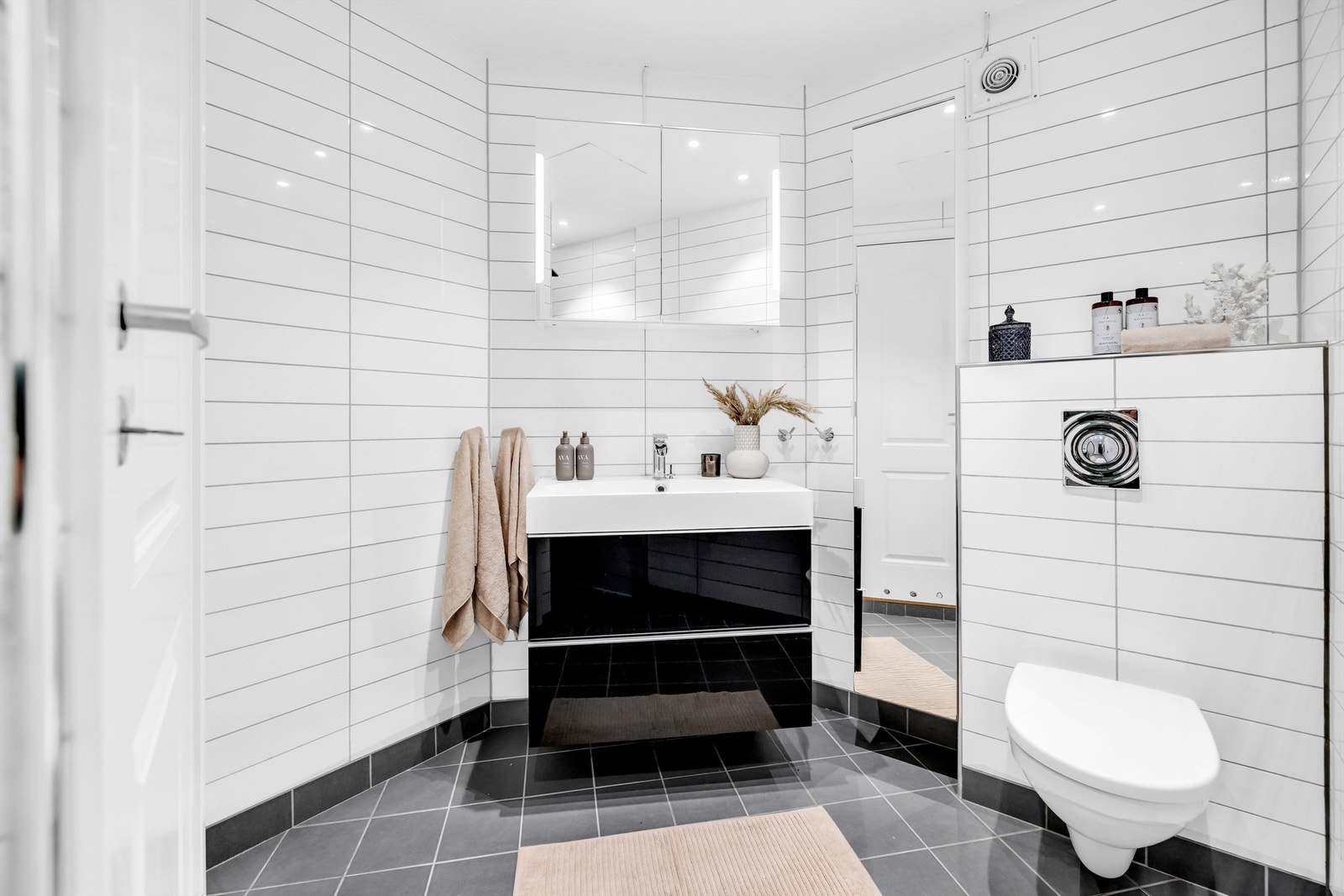 Badet er innredet med et vegghengt klosett, servant nedfelt i en skuffeseksjon og speil med integrert belysning. Det er opplegg for vaskemaskin. Galleribilde