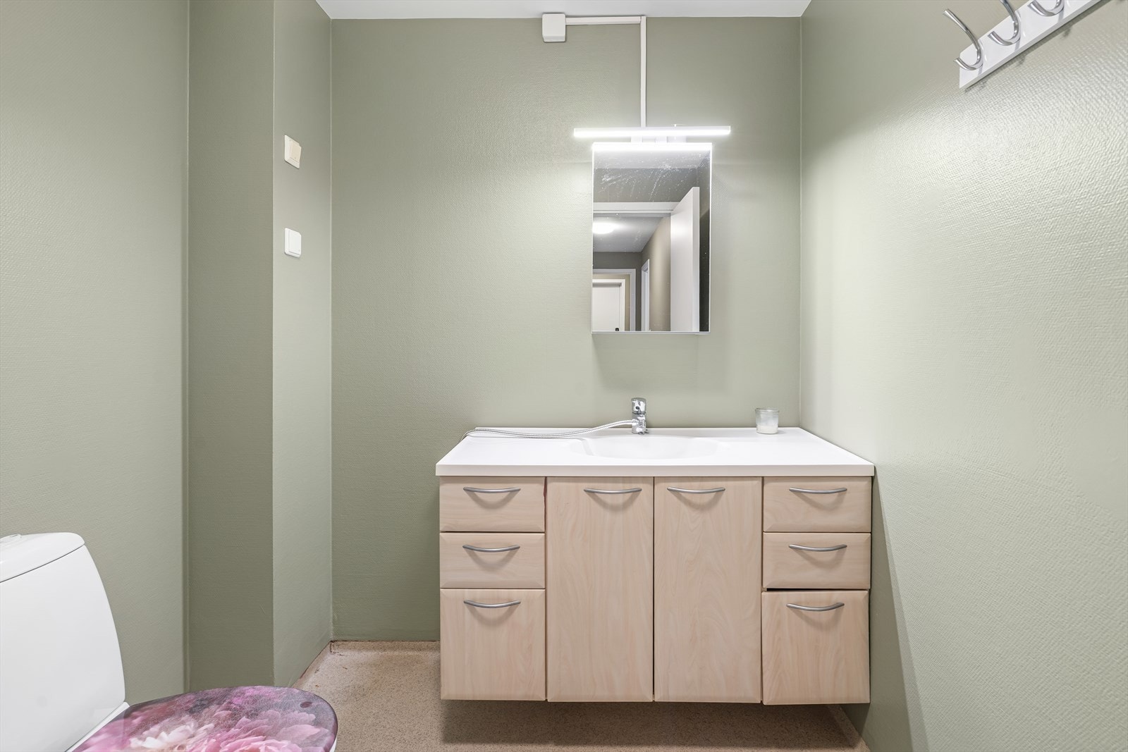 Badet ligger også i 1.etasje, og er utstyrt med servantinnredning med skuffer og speilskap. Veggene har malt strie. Galleribilde