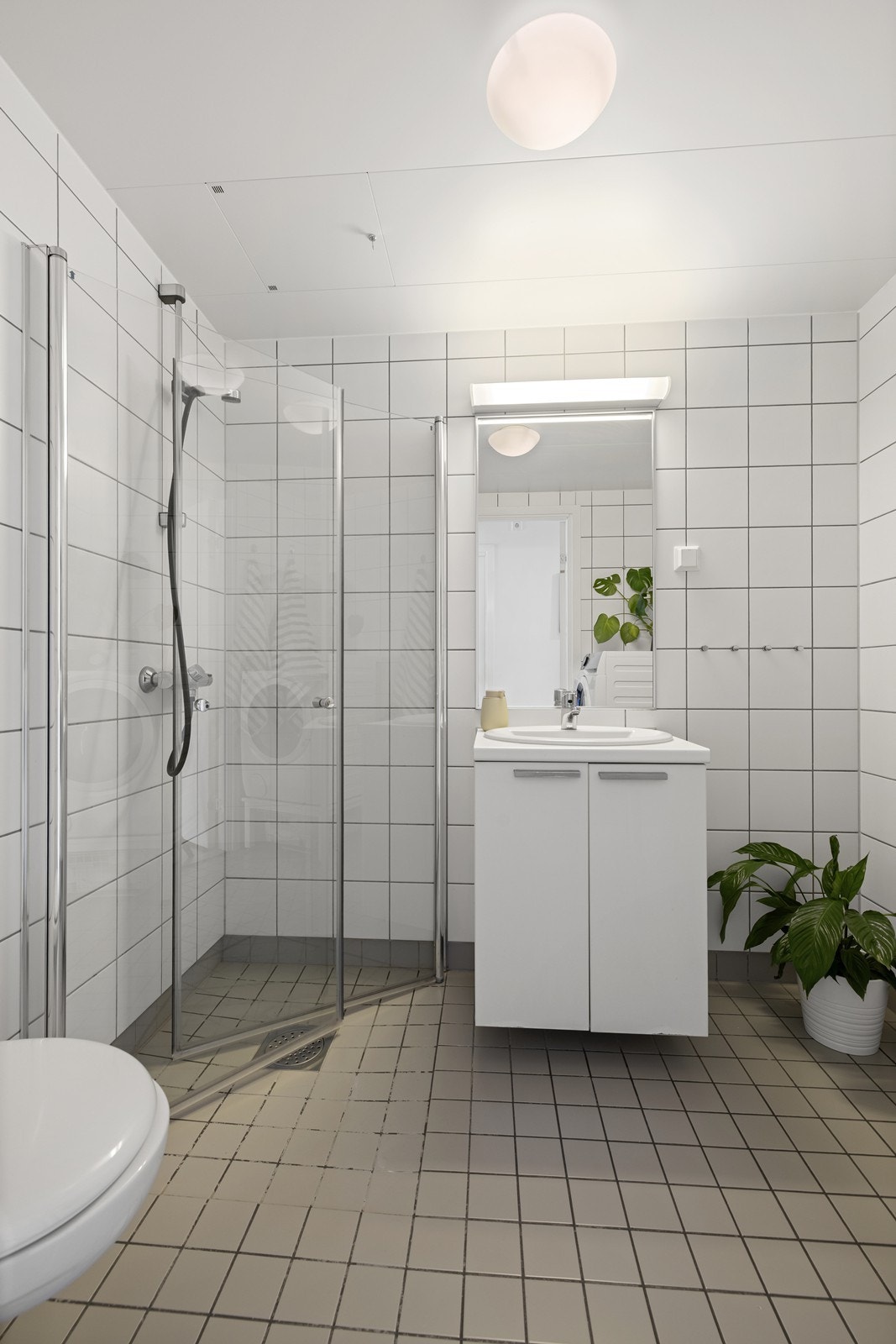 Badet er praktisk innredet med dusjhjørne med glassdører, vegghengt toalett og opplegg for vaskemaskin. Galleribilde