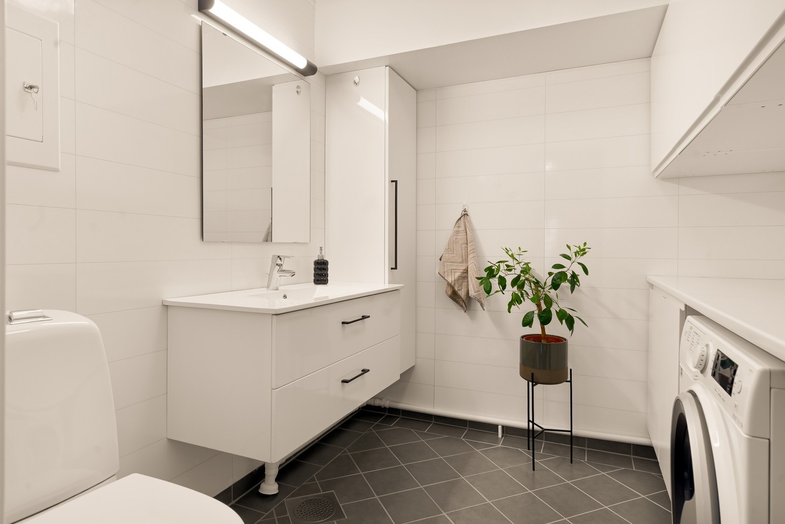 Vegg-i-vegg med badet ligger dette vaskerommet, som også har toalett, servant med to store skuffer og skapplass. Galleribilde