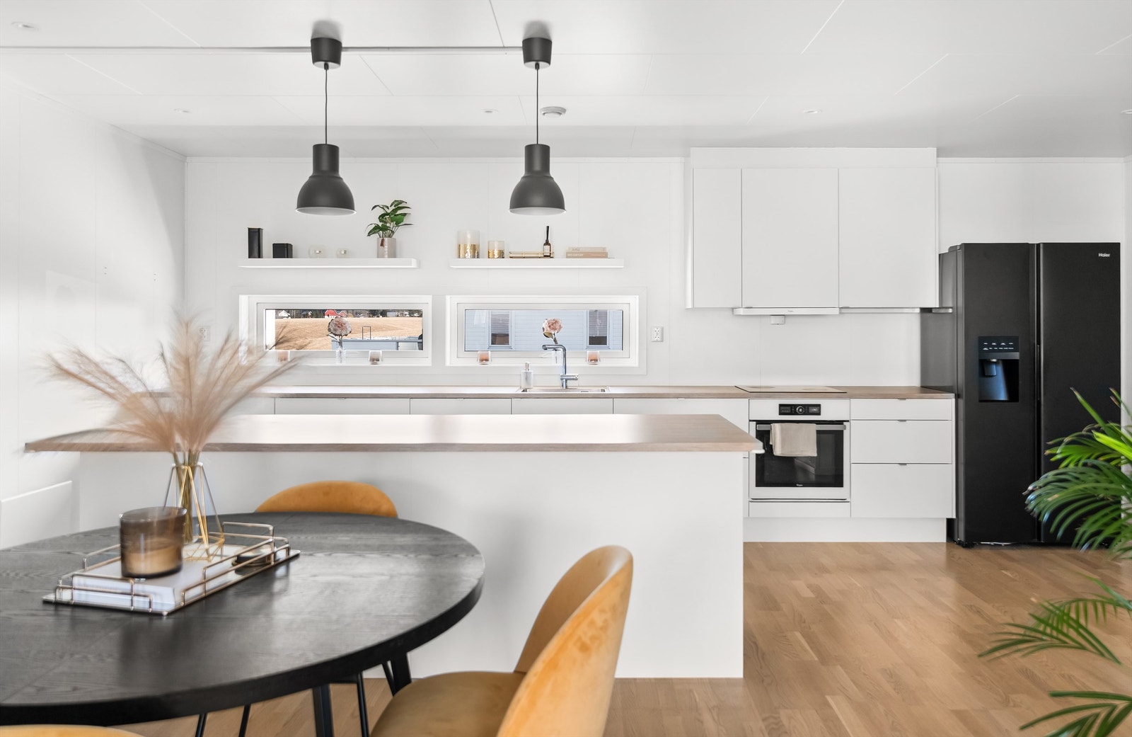 Kjøkkeninnredning fra Sigdal med hvite, glatte fronter, laminatbenkeplate og integrert komfyr og oppvaskmaskin. Galleribilde
