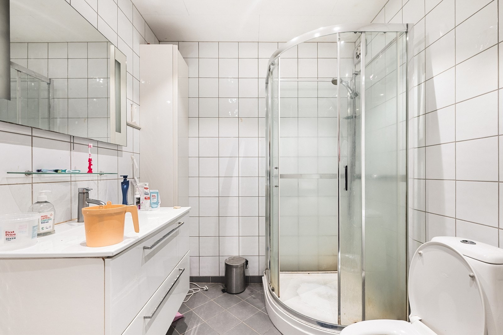 Helfliset bad med varme i gulv. Badet er innredet med toalett, vask med under- og overskap, høyskap og dusjkabinett. Galleribilde