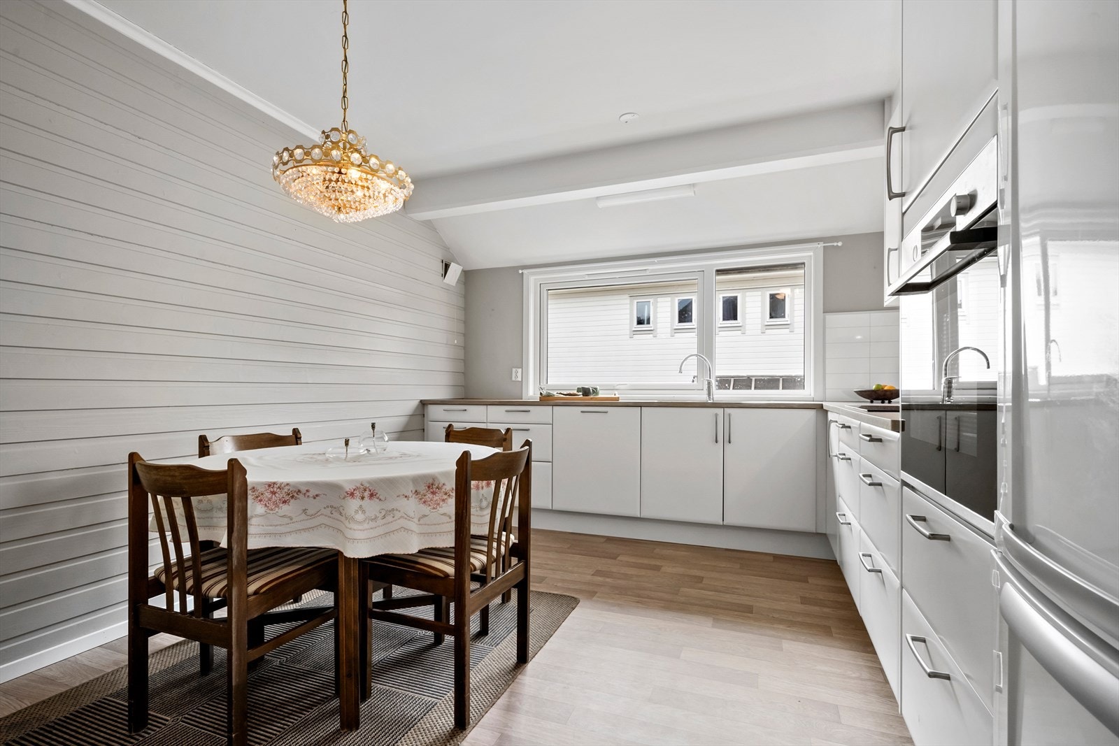 Tidløs kjøkkeninnredning med hvite glatte fronter og benkeplate i lamninat. Galleribilde