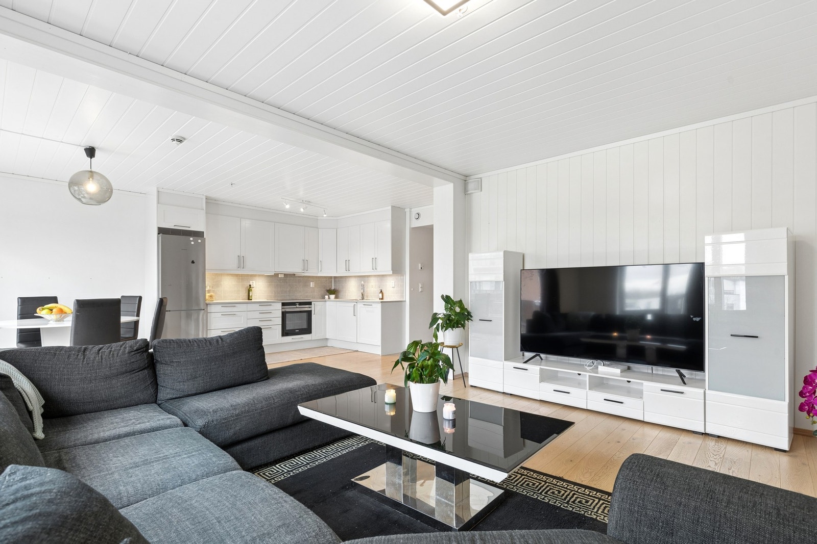 Den åpne løsningen mot kjøkken og spiseplass gir en sosial og moderne romfølelse. Galleribilde