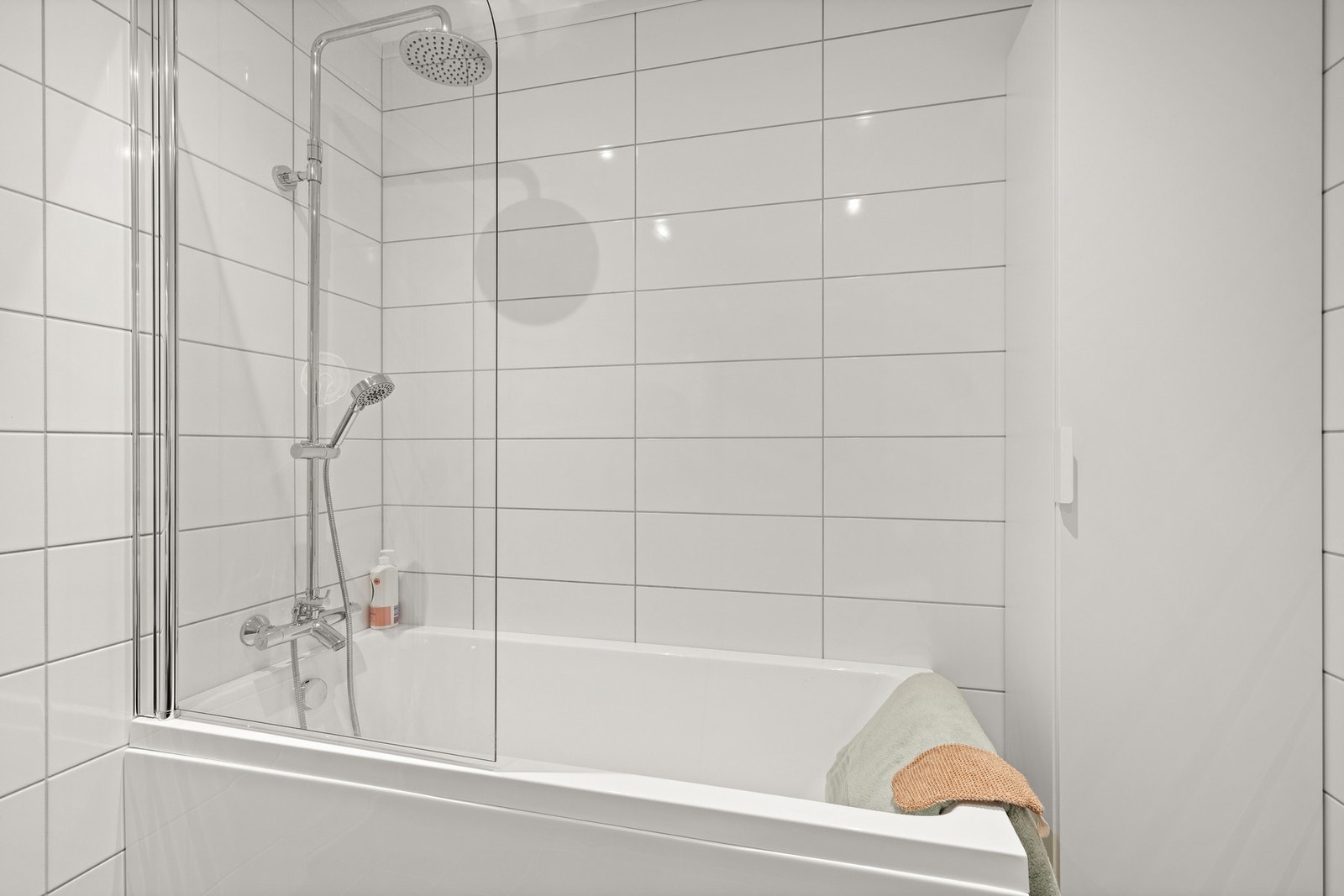 Badet har badekar med takdusj montert på vegg, varmekabler og opplegg for vaskemaskin Galleribilde