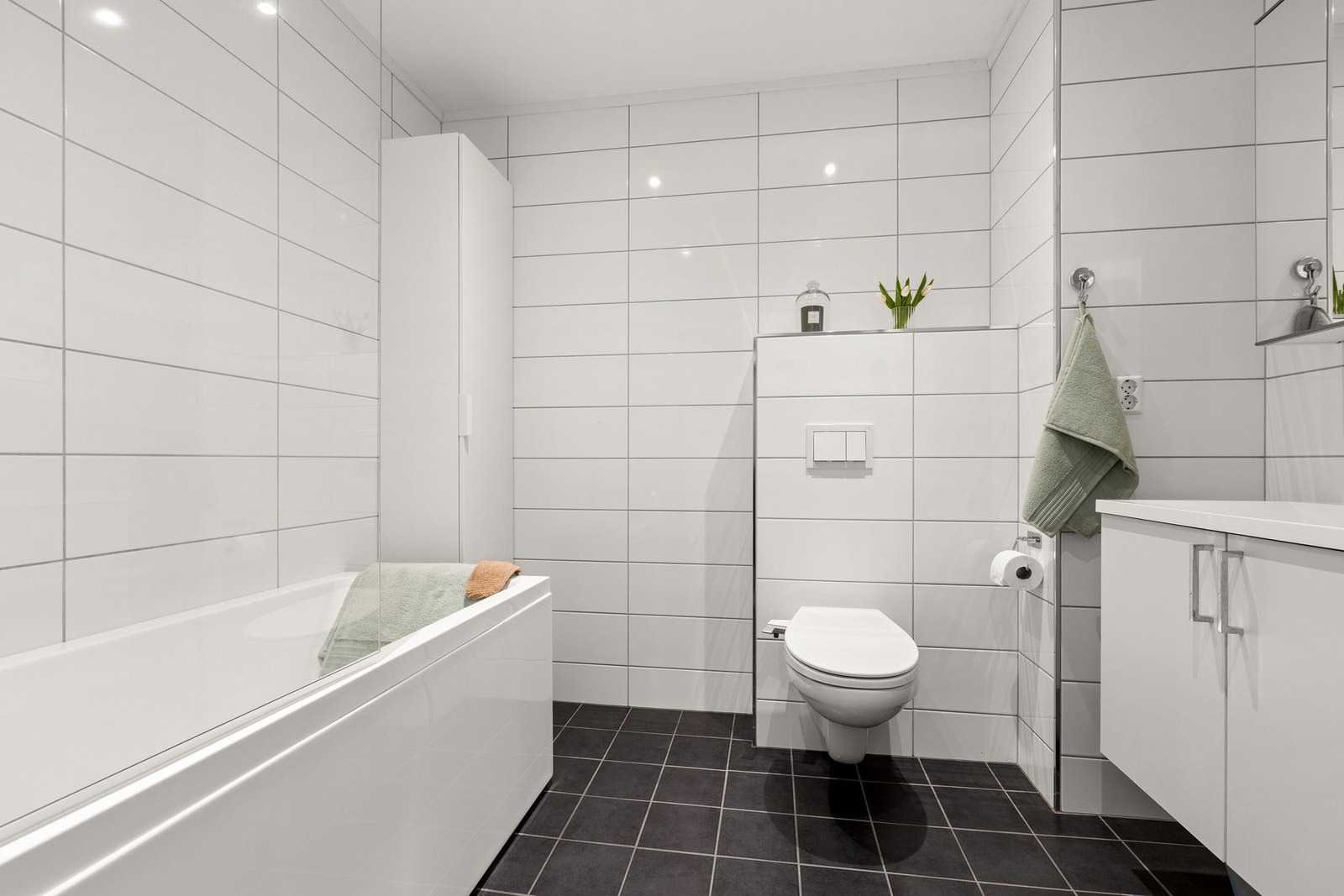 Badet i boligens andre etasje er fra 2019 med hvite fliser på veggene og mørkegrå på gulvet. Badekaret er oppgradert fra standard leveranse Galleribilde