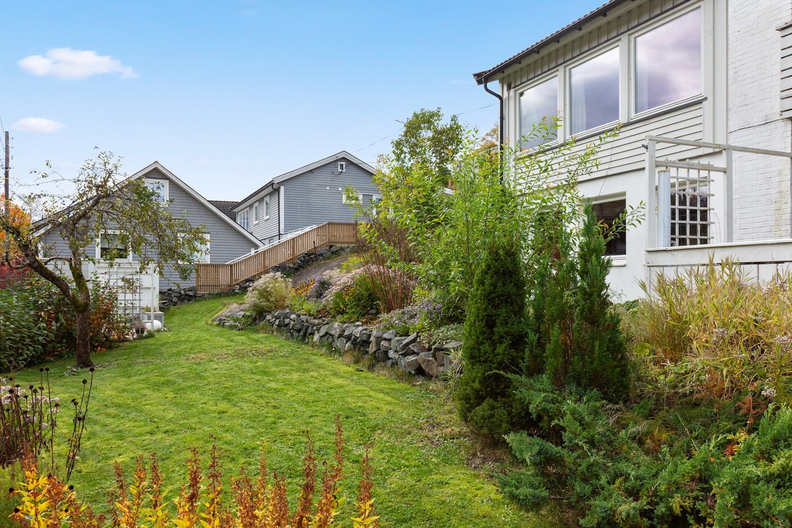 Eiendommen ligger i skrånende terreng med en pent opparbeidet natursteinsmur. Galleribilde