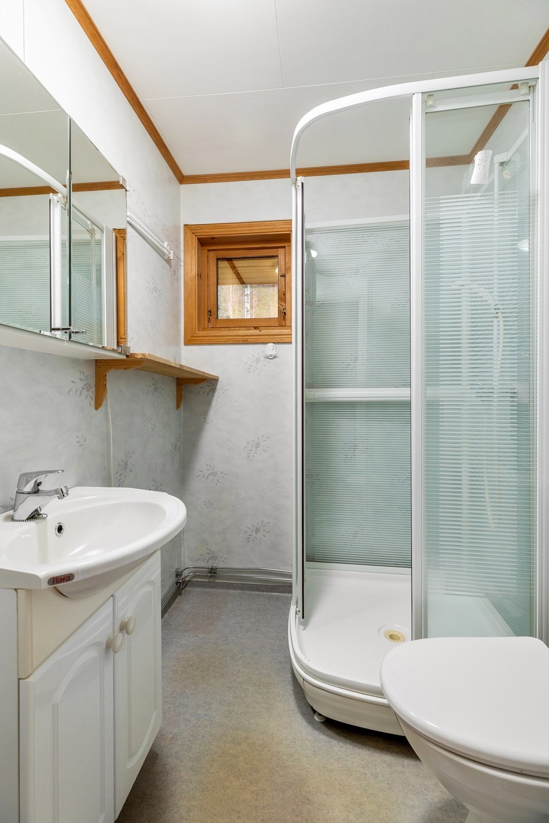 Bad i hovedetasjen med belegg på gulv og våtromstapet på vegger. Rommet er innredet med dusjkabinett, wc og servant med tilhørende innredning. Naturlig ventilasjon. Galleribilde