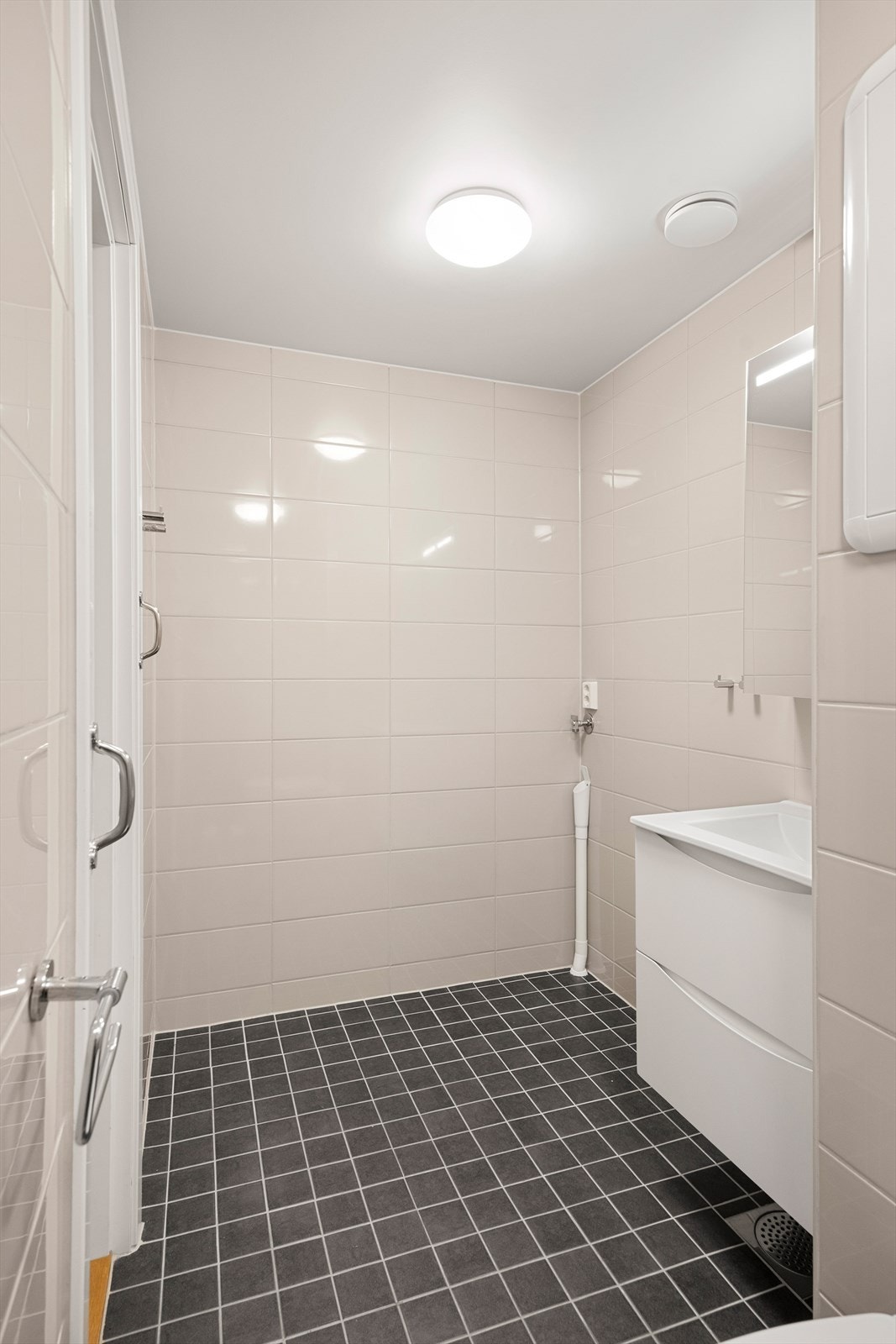 Badet er innredet med servant, dusj med innfelbare glassdører, vegghengt toalett og opplegg for vaskemaskin. Galleribilde