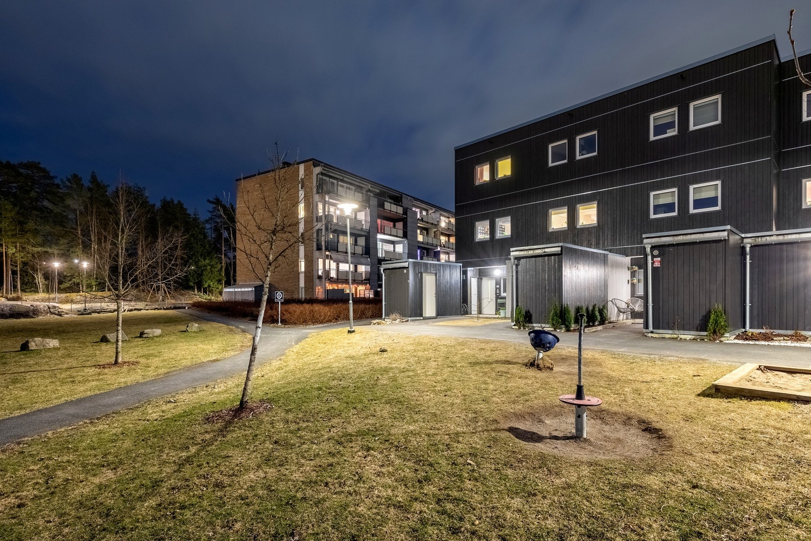 Felles tomteområde er pent opparbeidet med gressplen, ulik beplantning og gjesteparkeringer. Galleribilde