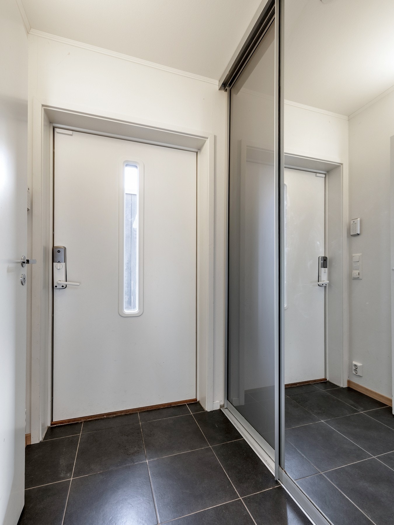 Vel innenfor døren ønskes du velkommen av et stilrent entréområde med flislagt gulv utstyrt med komfortabel gulvvarme og skyvedørsgarderobe. Galleribilde