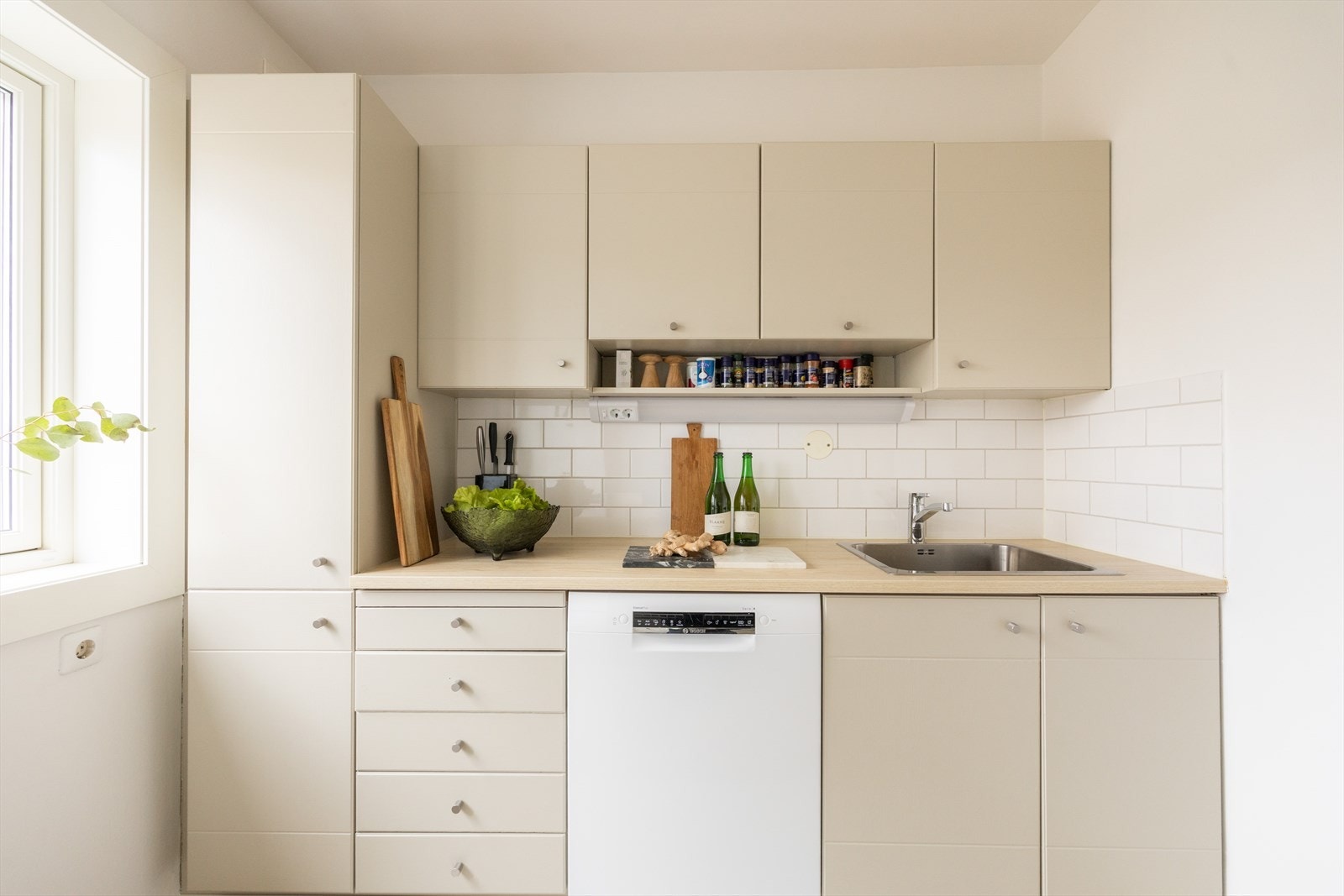 Kjøkkeninnredningen består av beige, glatte fronter og benkeplate av laminat med nedfelt vask. Galleribilde