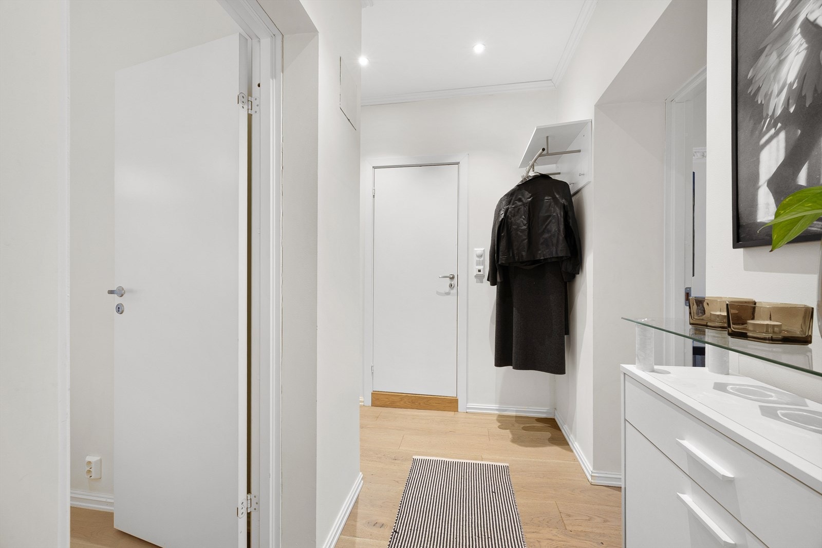 Gangen ønsker velkommen inn med gjennomgående laminatgulv og malte flater, som i resten av boligen. Galleribilde