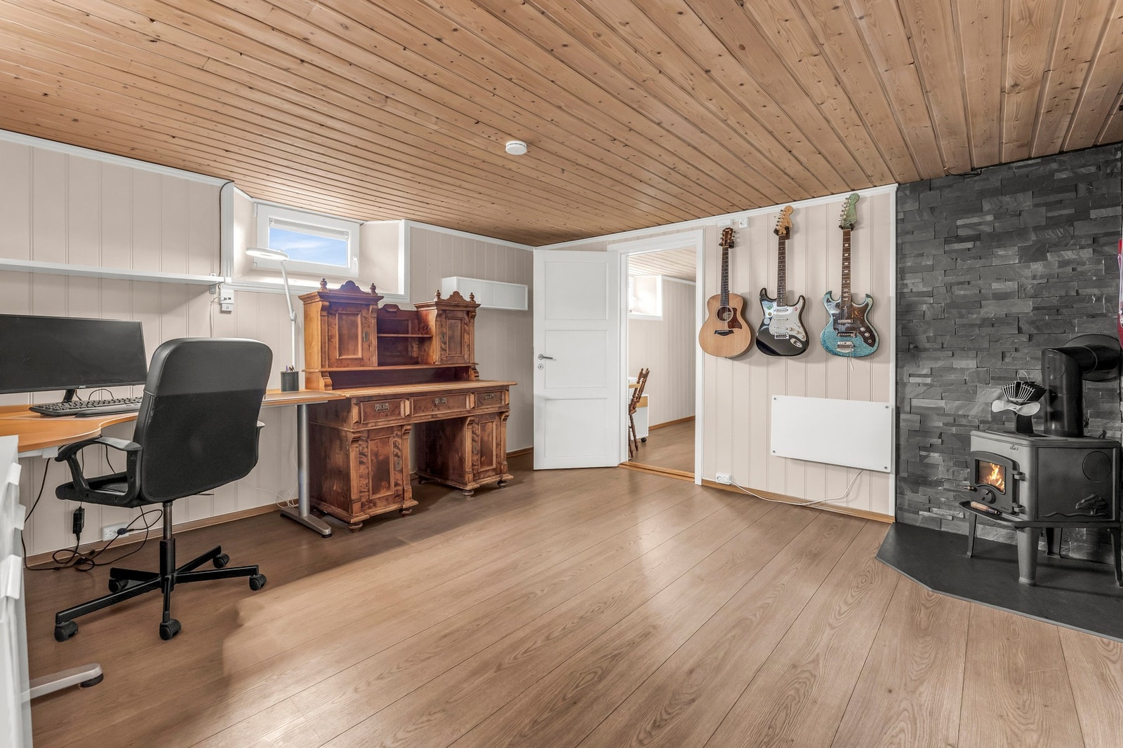 Romslig rom med trepanel i taket og peisovn. Galleribilde