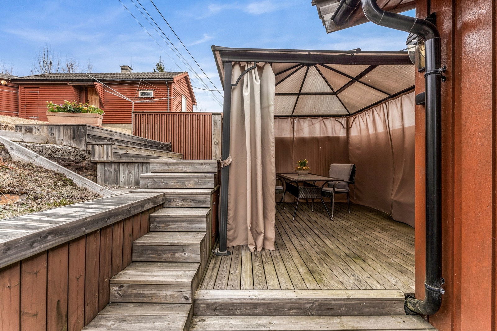 Uteområde med overbygd sittegruppe og tretrapp som leder opp til terrassen. Galleribilde