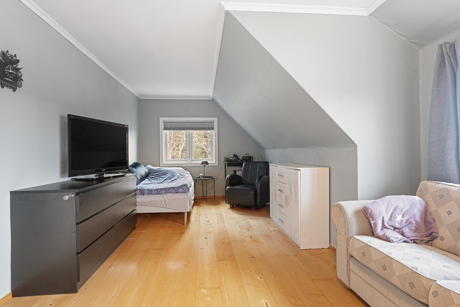 Den romslige loftstuen har god plass til sofagruppe, seng og kommoder/oppbevaring Galleribilde