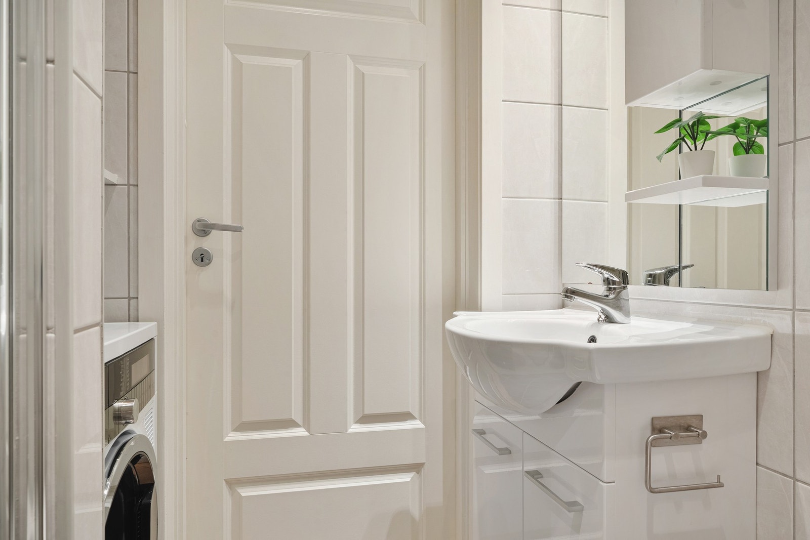 Badet er innredet med vegghengt toalett, dusj med glassvegger, og baderomsmøblement med speil og belysning. Galleribilde
