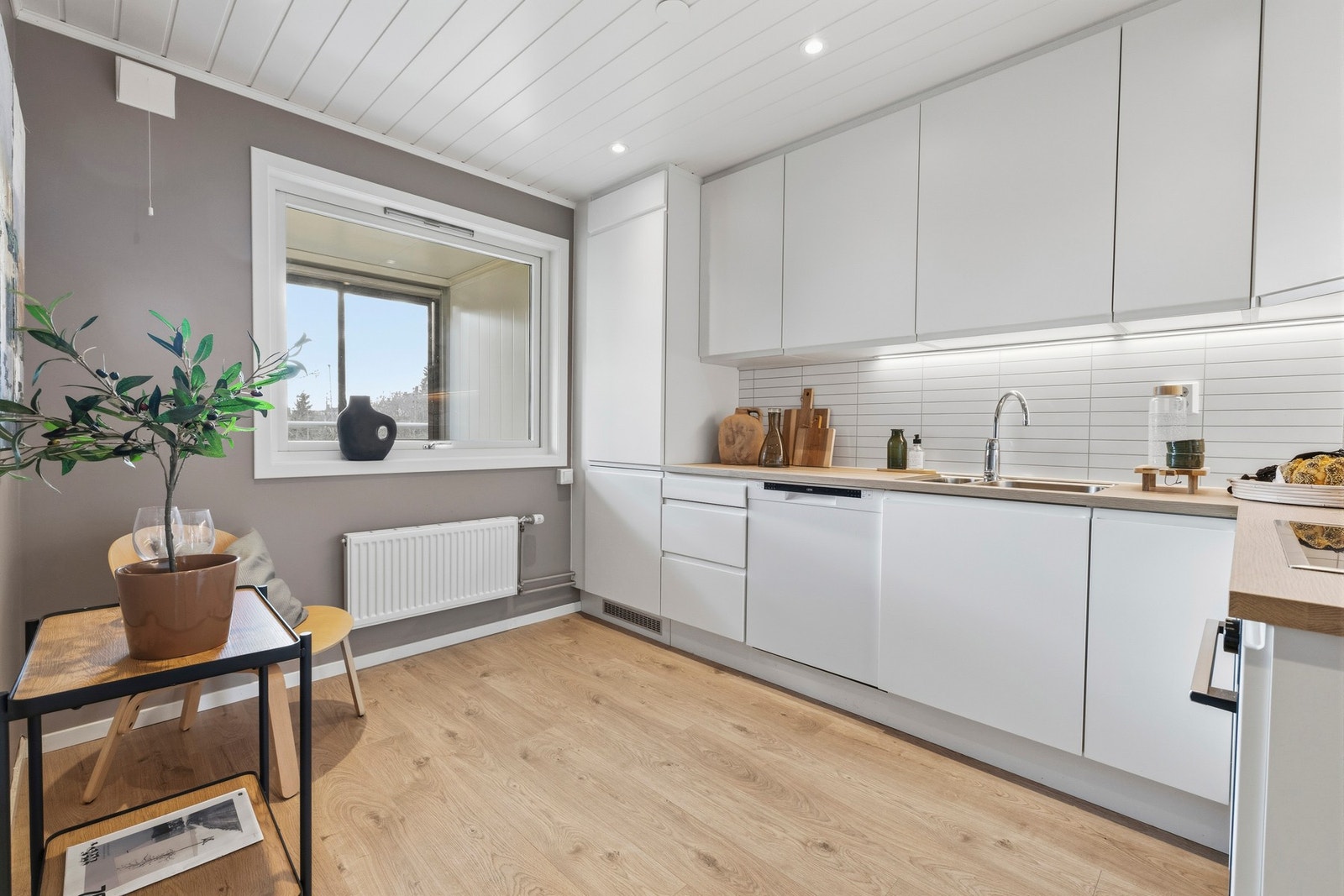 Kjøkkenet var nytt i 2020, og har godt med skap- og benkeplass. Innredningen har malte fronter, laminat benkeplater, oppvaskkum, ventilator og plater over benk. Galleribilde