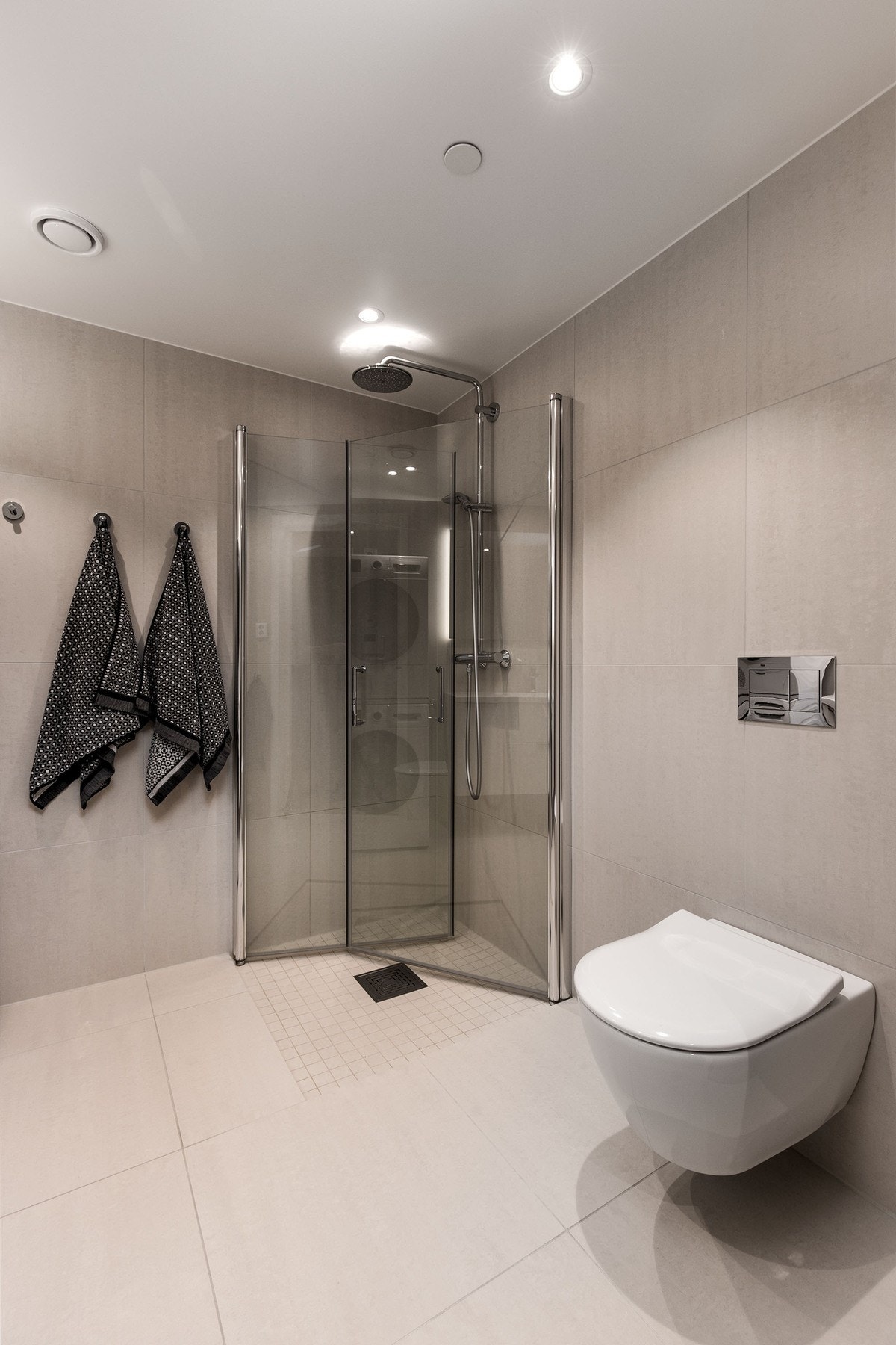 Badet har dusjløsning med glassdører og vegghengt toalett med innebygget sisterne. Galleribilde