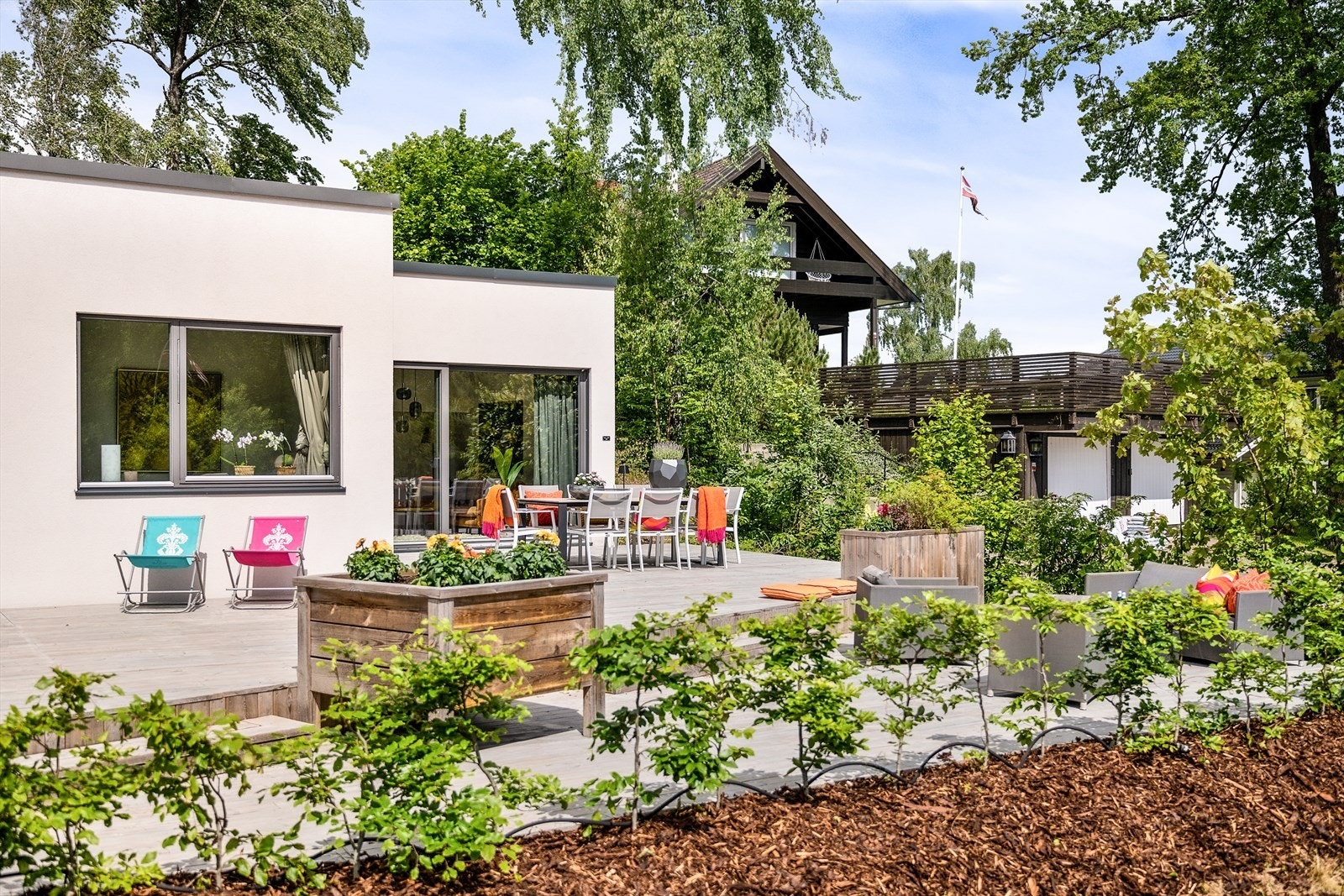Terrassen er belagt med terrassebord og er vakkert opparbeidet med blomsterkasser og variert beplantning som gir liv og farge til uterommet. Galleribilde